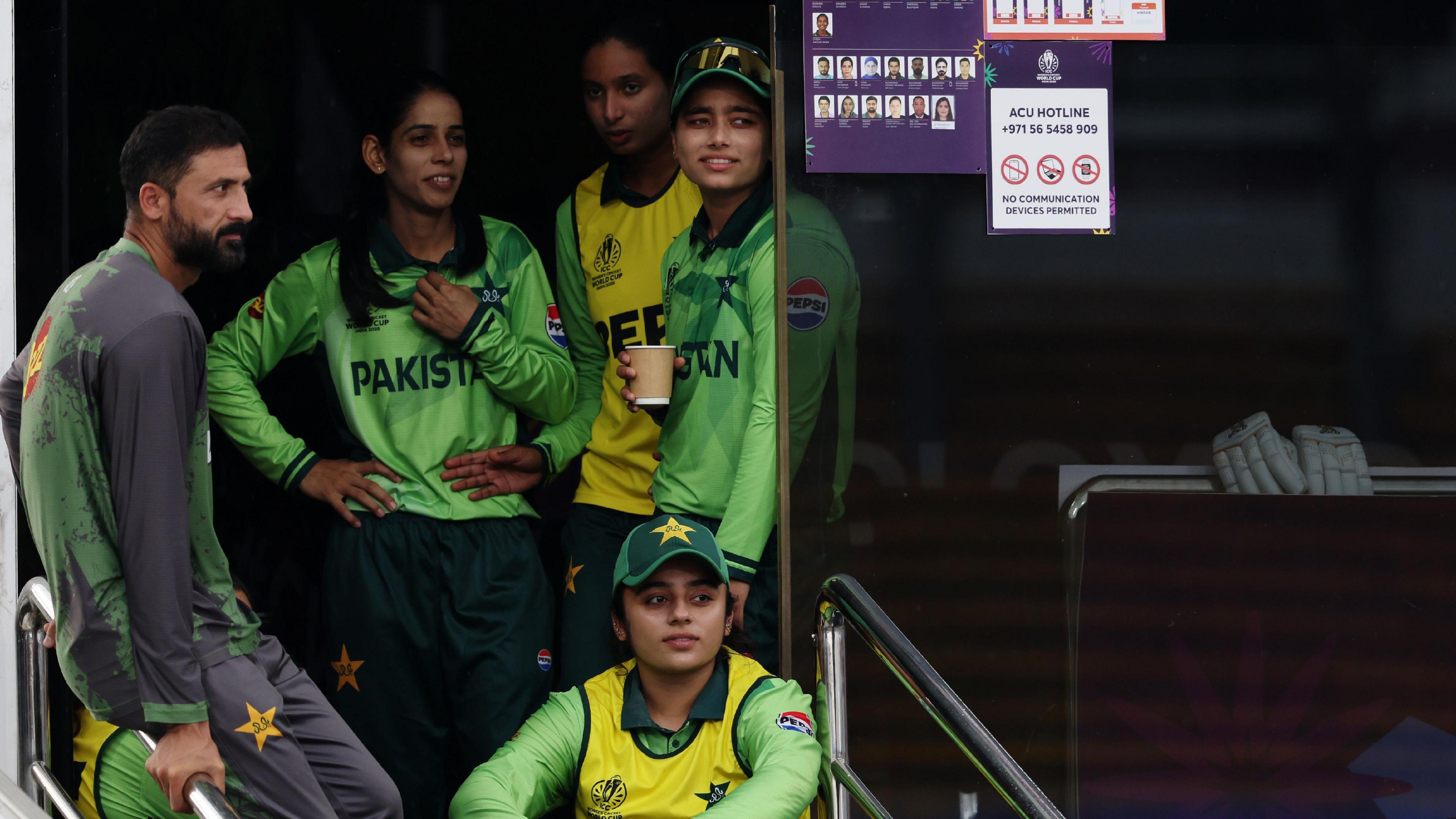 Pakistan players and staff looking out onto the ground from the dressing room