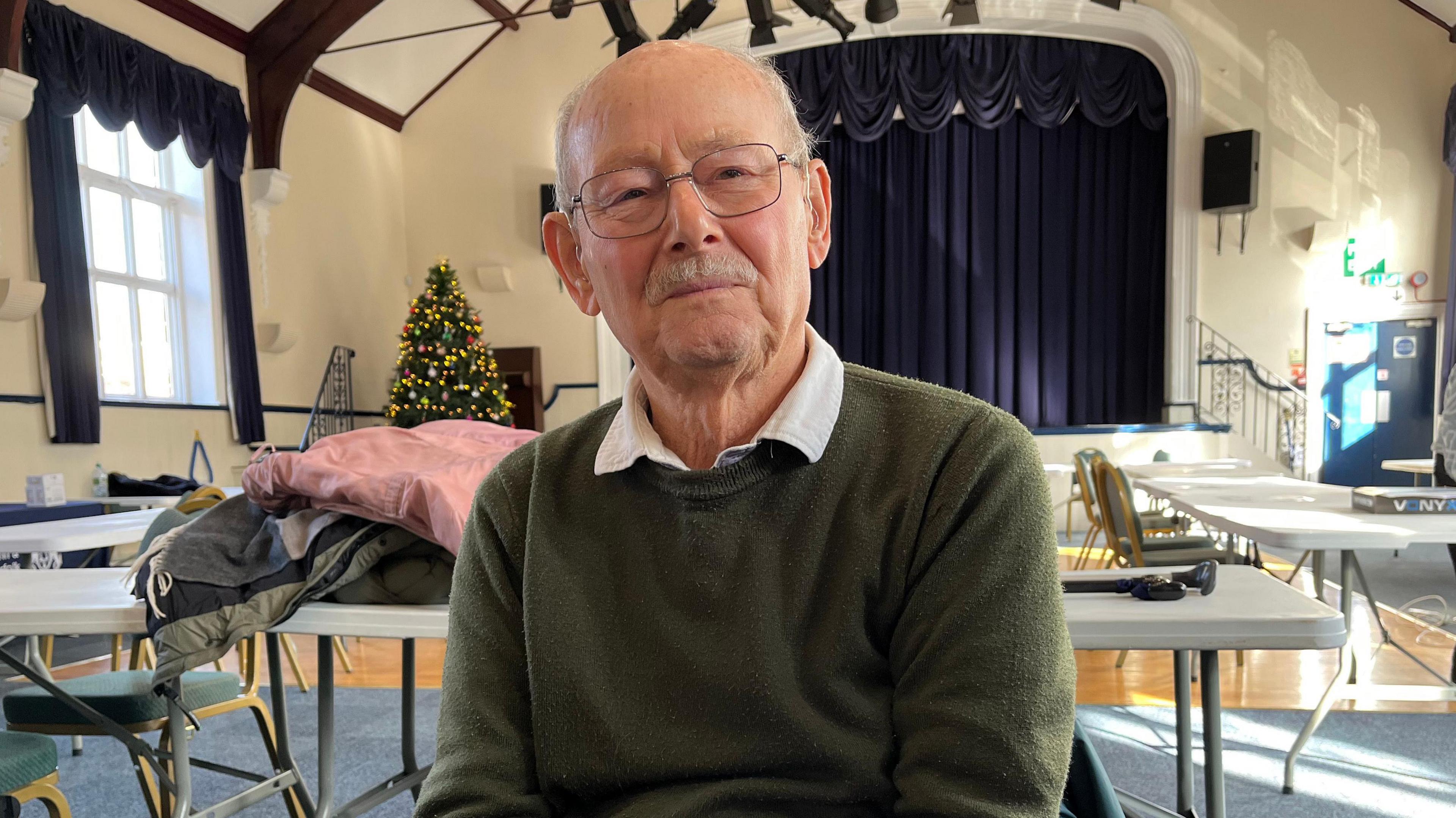 Richard Carter wears glasses and an olive sweatshirt. He has a grey moustache.