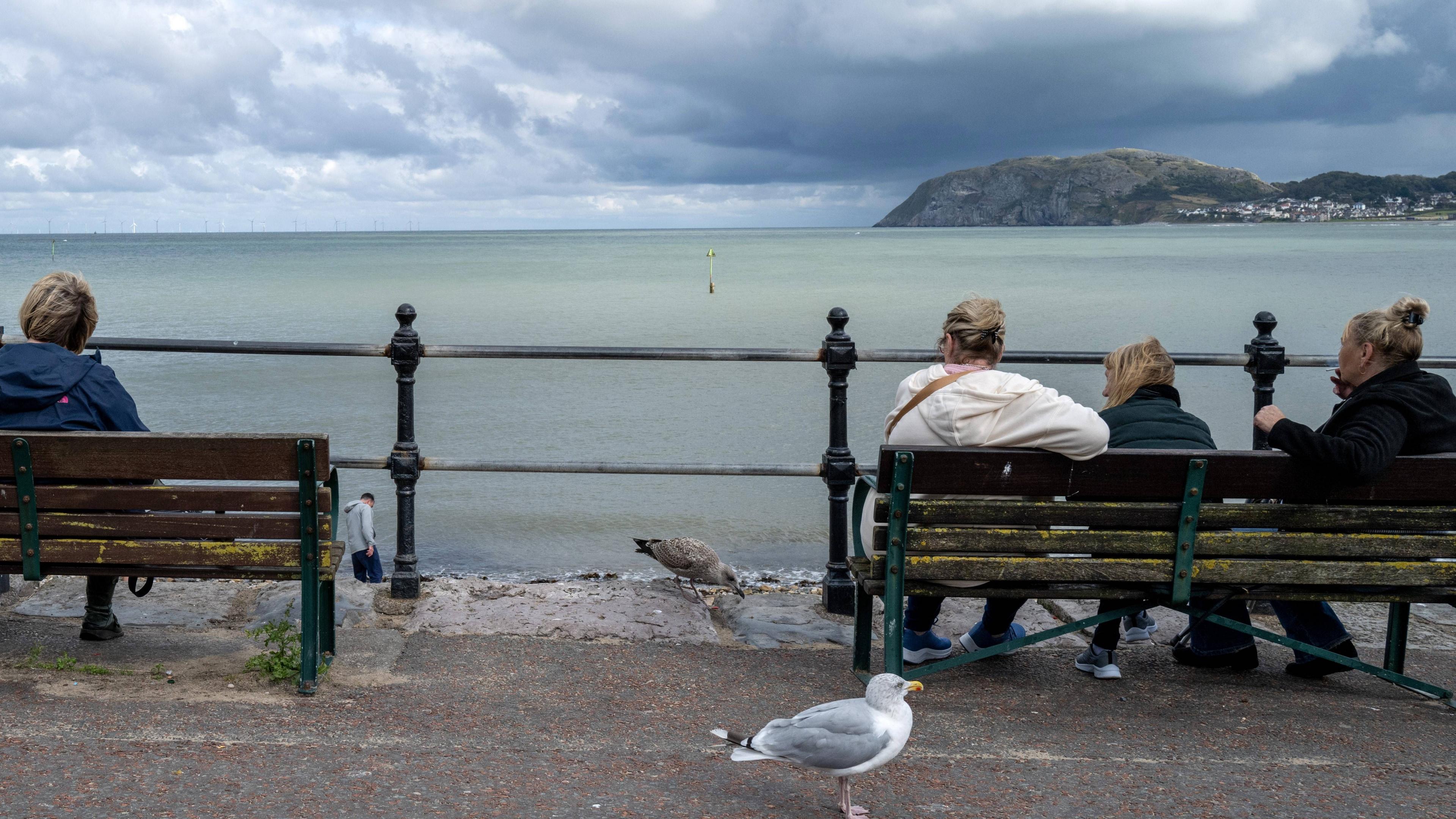 Twristiaid ger y mor yn Llandudno