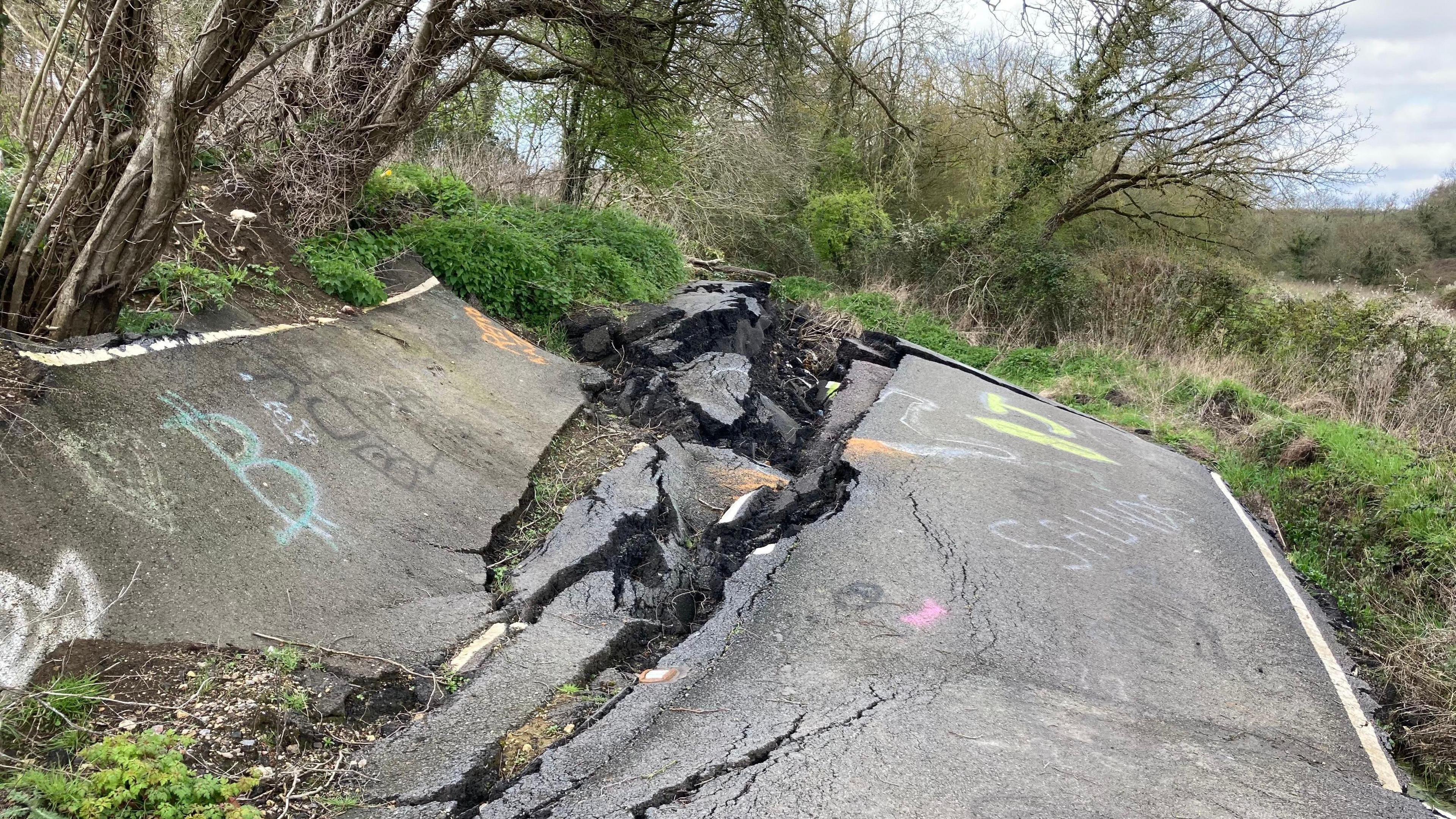 B4069 Lyneham Banks. The road is all broken up and the tarmac is at various angles, following a landslip