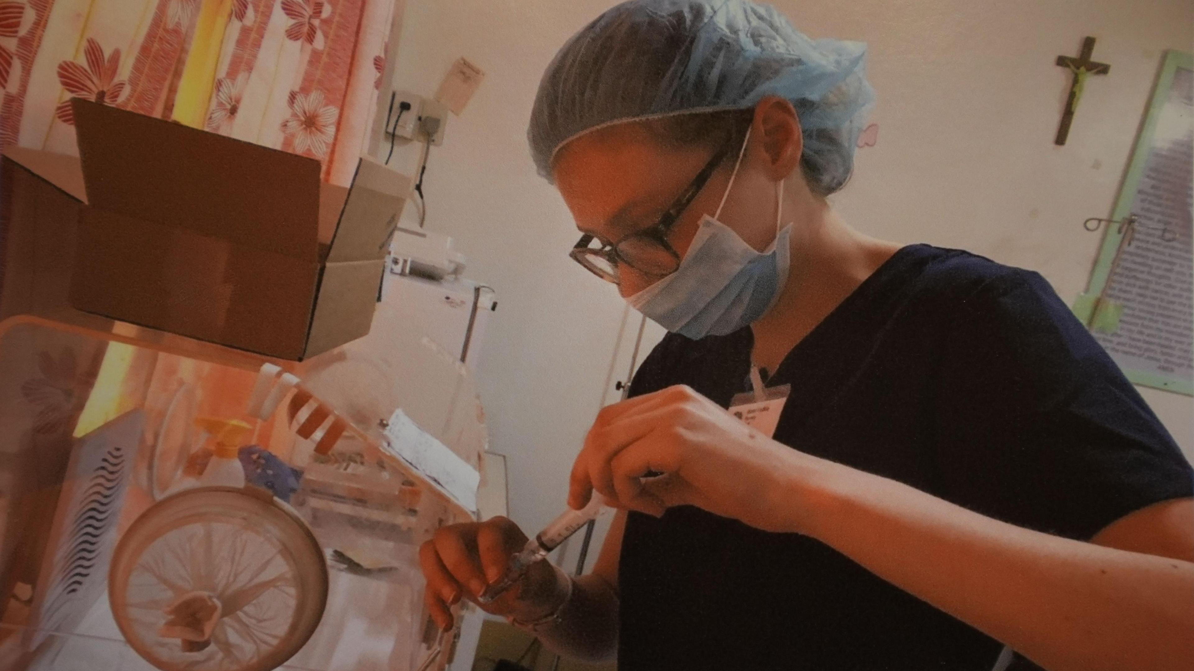 Mared Foulkes inside a hospital in the Philippines wearing medical scrubs and a face mask, carrying out pharmacy work