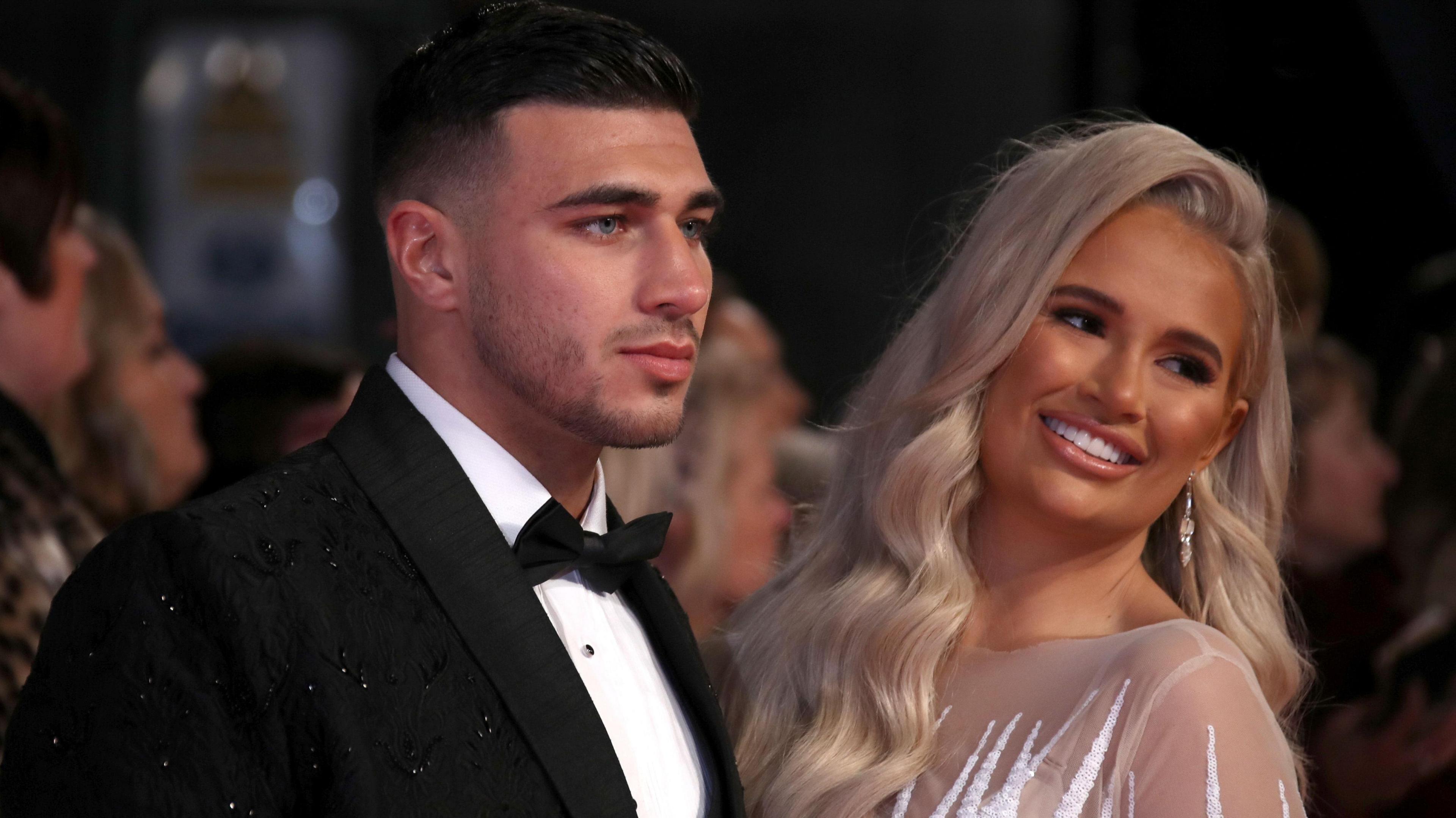 Tommy Fury in a black suit and Molly-Mae Hague in a light coloured dress