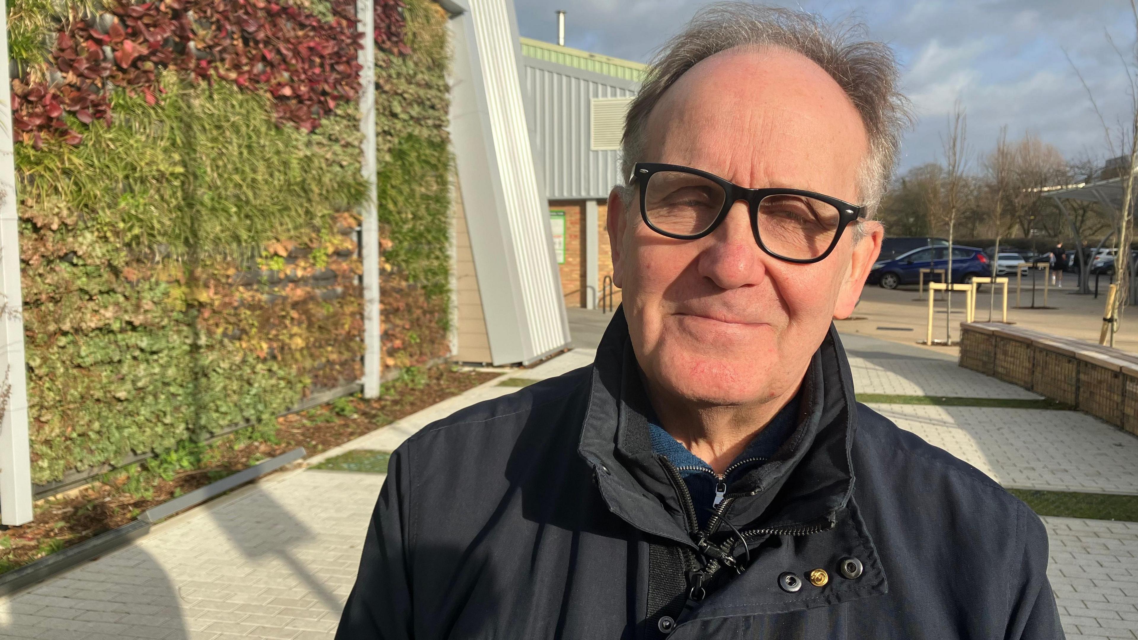 Bob Deering wearing black-rimmed glasses and a dark blue coat.