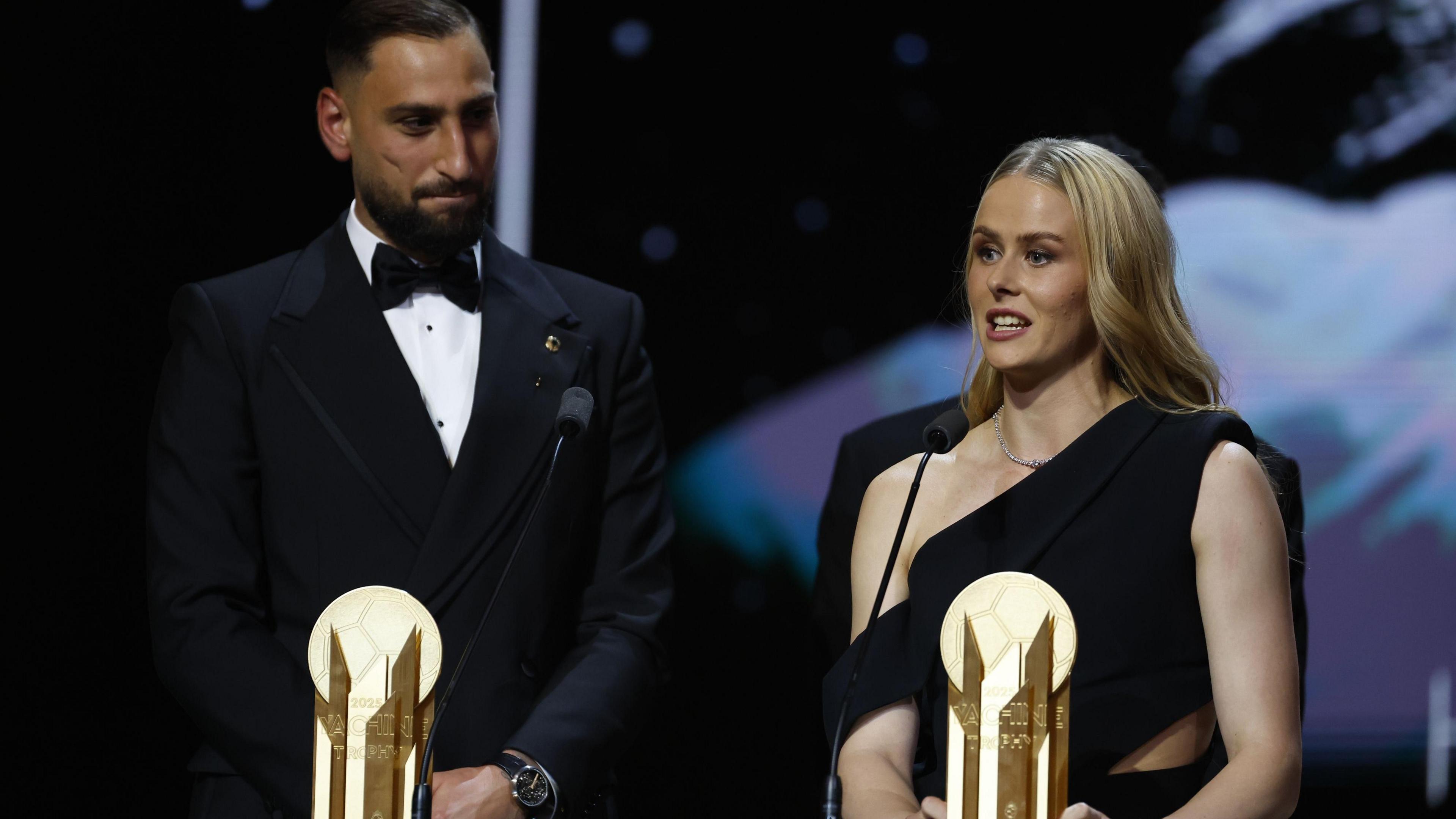 Italy's goalkeeper Gianluigi Donnarumma on the left wearing a black suit and white shirt and England's goalkeeper Hannah Hampton wearing a black one-shouldered dress stand side by side in front of microphones and their Yashin Trophies during the Ballon d'Or 2025 ceremony at the Theatre du Chatelet in Paris