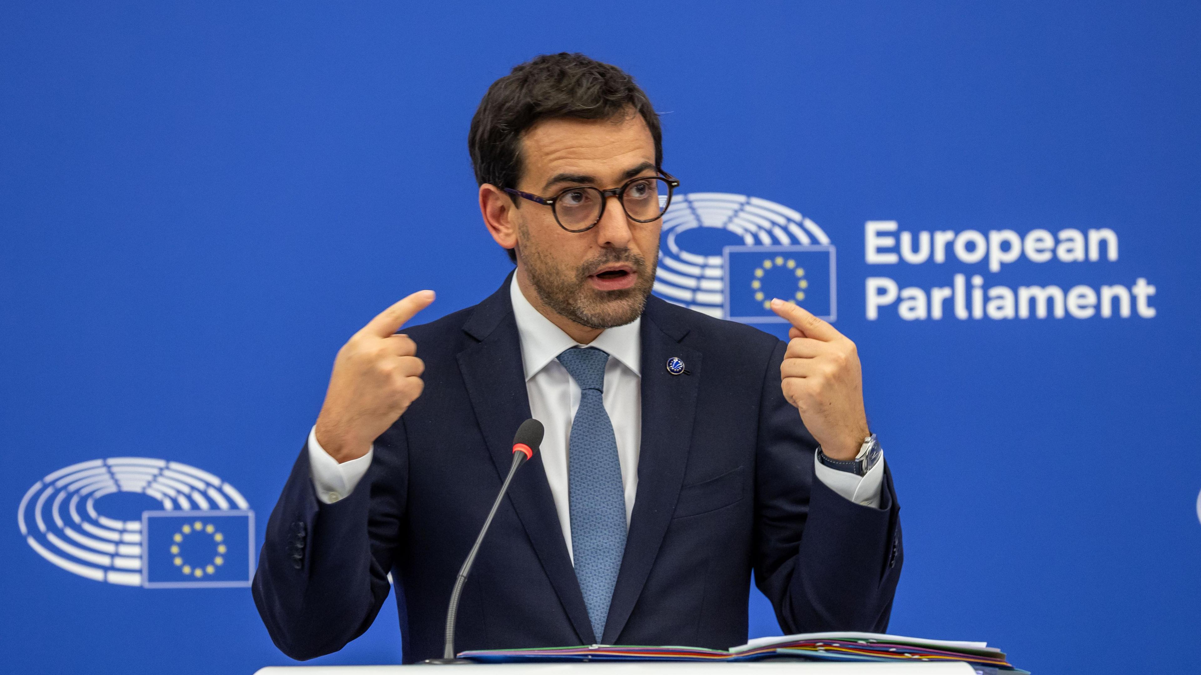 Stephane Sejourne, European Commission's Executive Vice-President for Prosperity and Industrial Strategy - he has dark hair, some dark stubble, and is standing at a lectern in front of the European Parliament - he appears to be mid-speaking and is pointing both of his own index fingers at his face