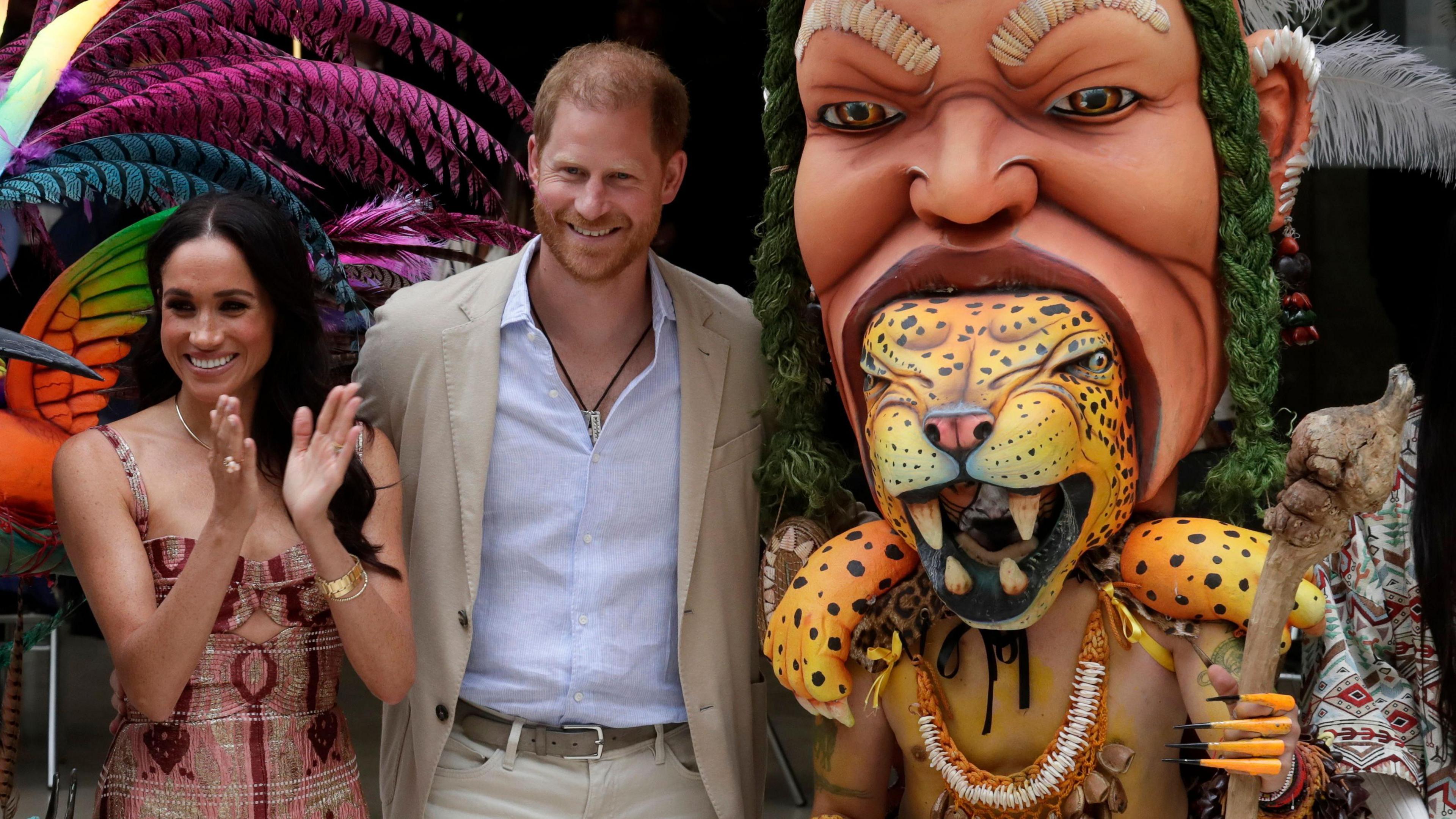 Prince Harry and Meghan pose for a photo with a figure of a big cat in the mouth of a person with a staff, during their visit in Bogota, Colombia, 15 August 2024.