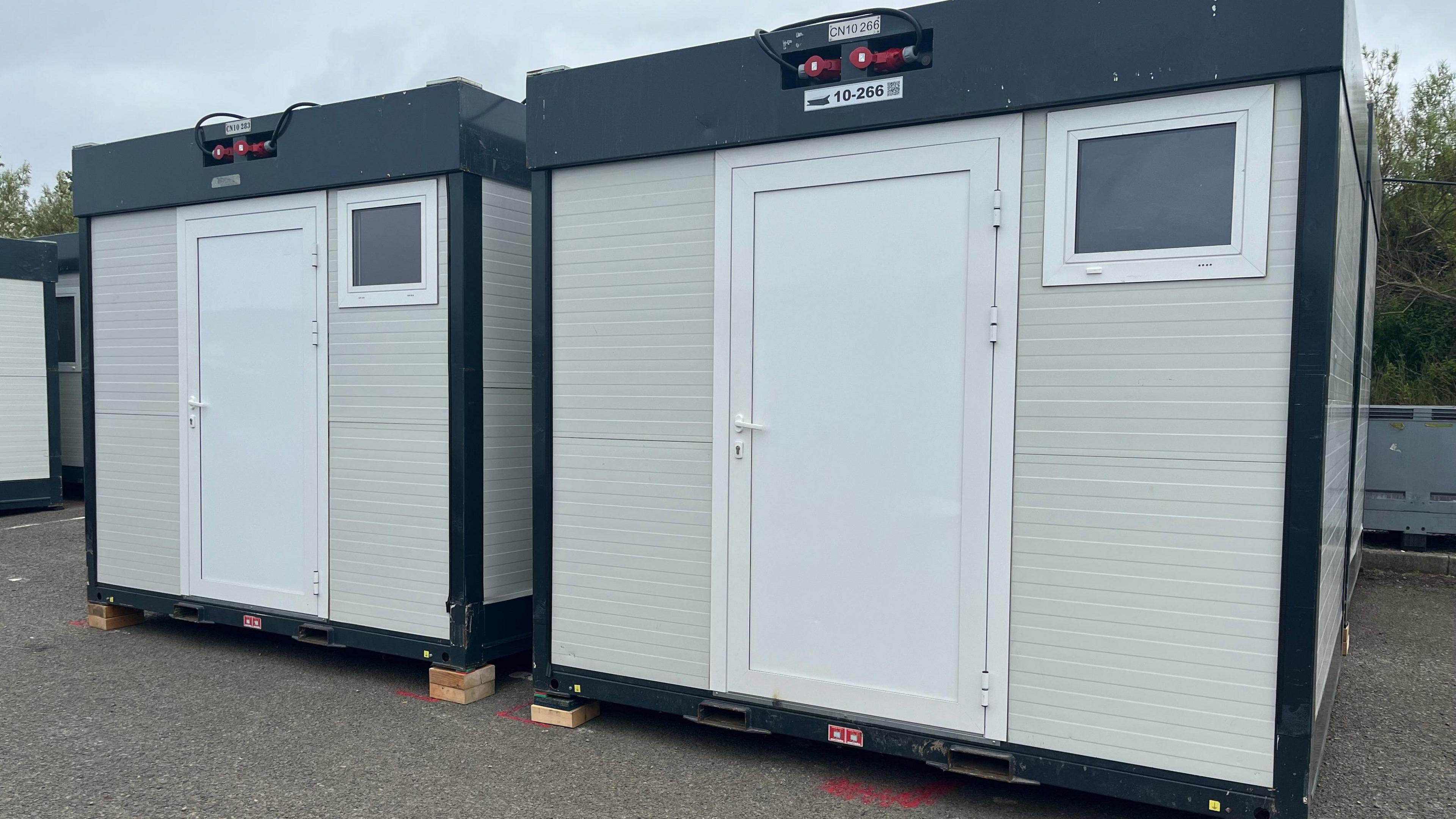 Two cuboid shaped units with a white door and a small window.