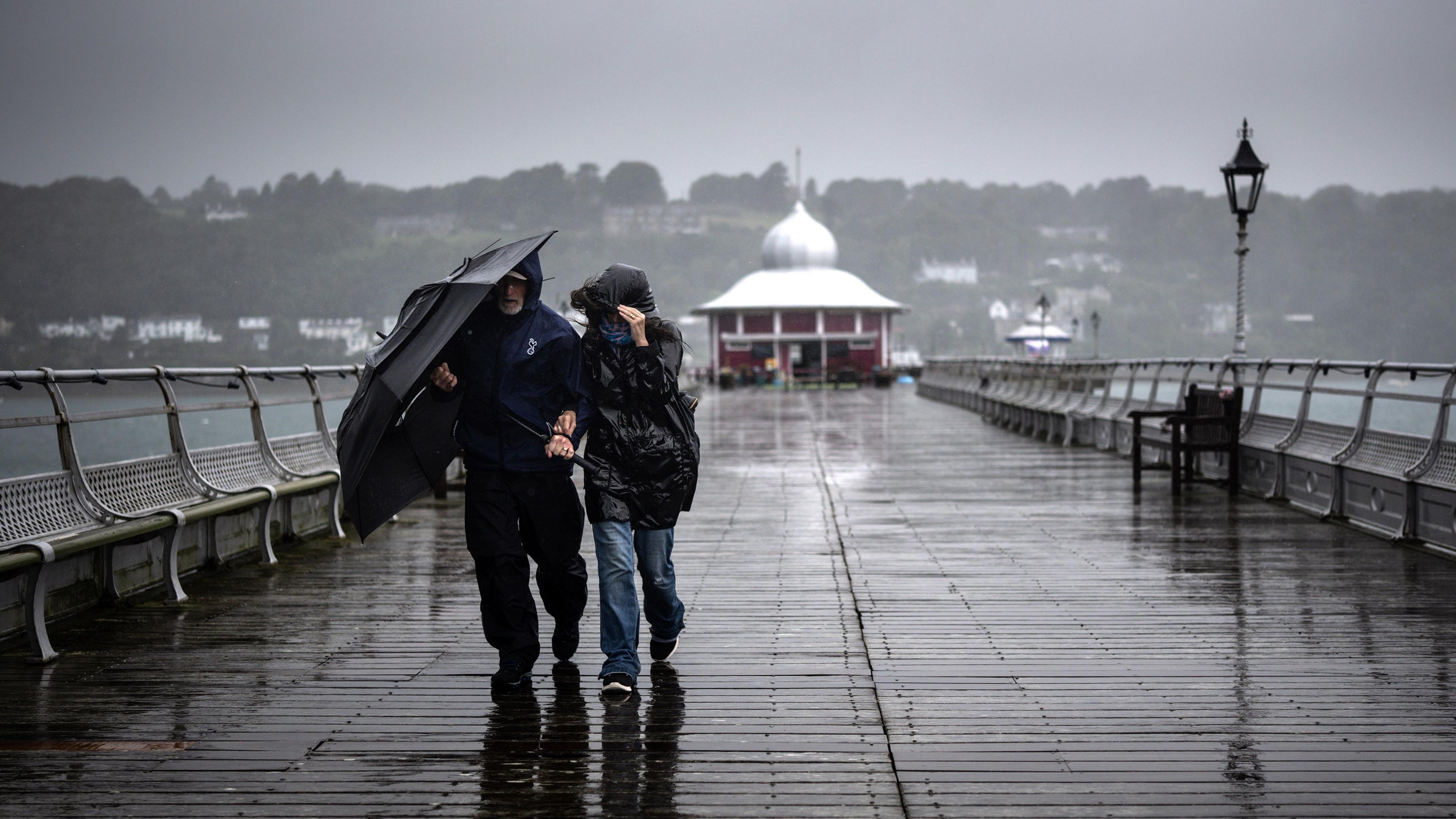 People battle against high winds and driving rain on a pier