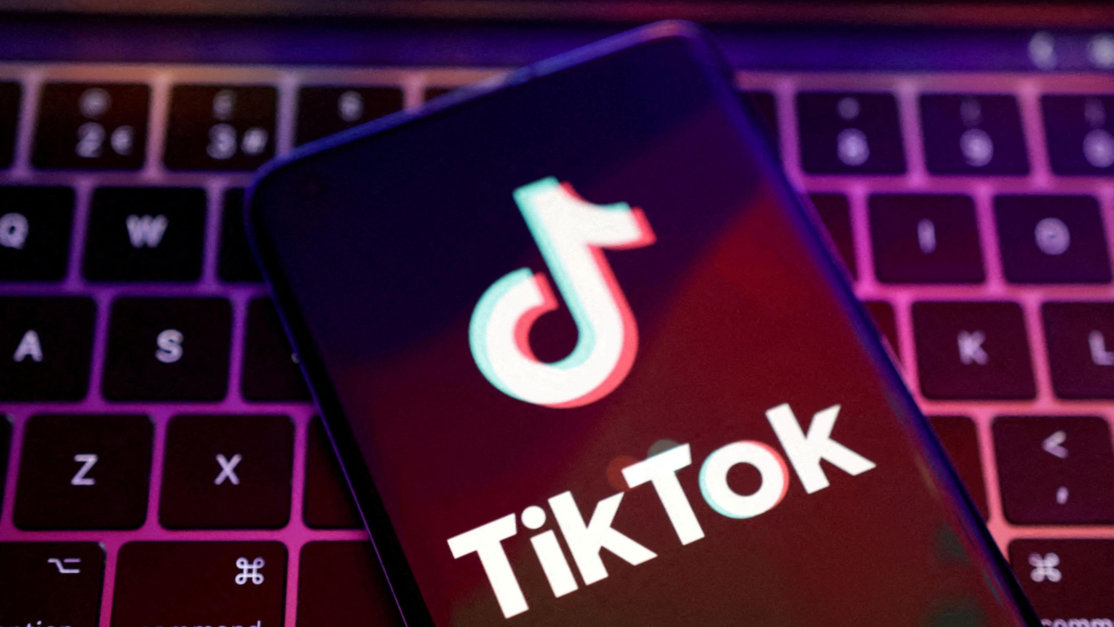 A phone displaying the TikTok song note logo lies on a keyboard