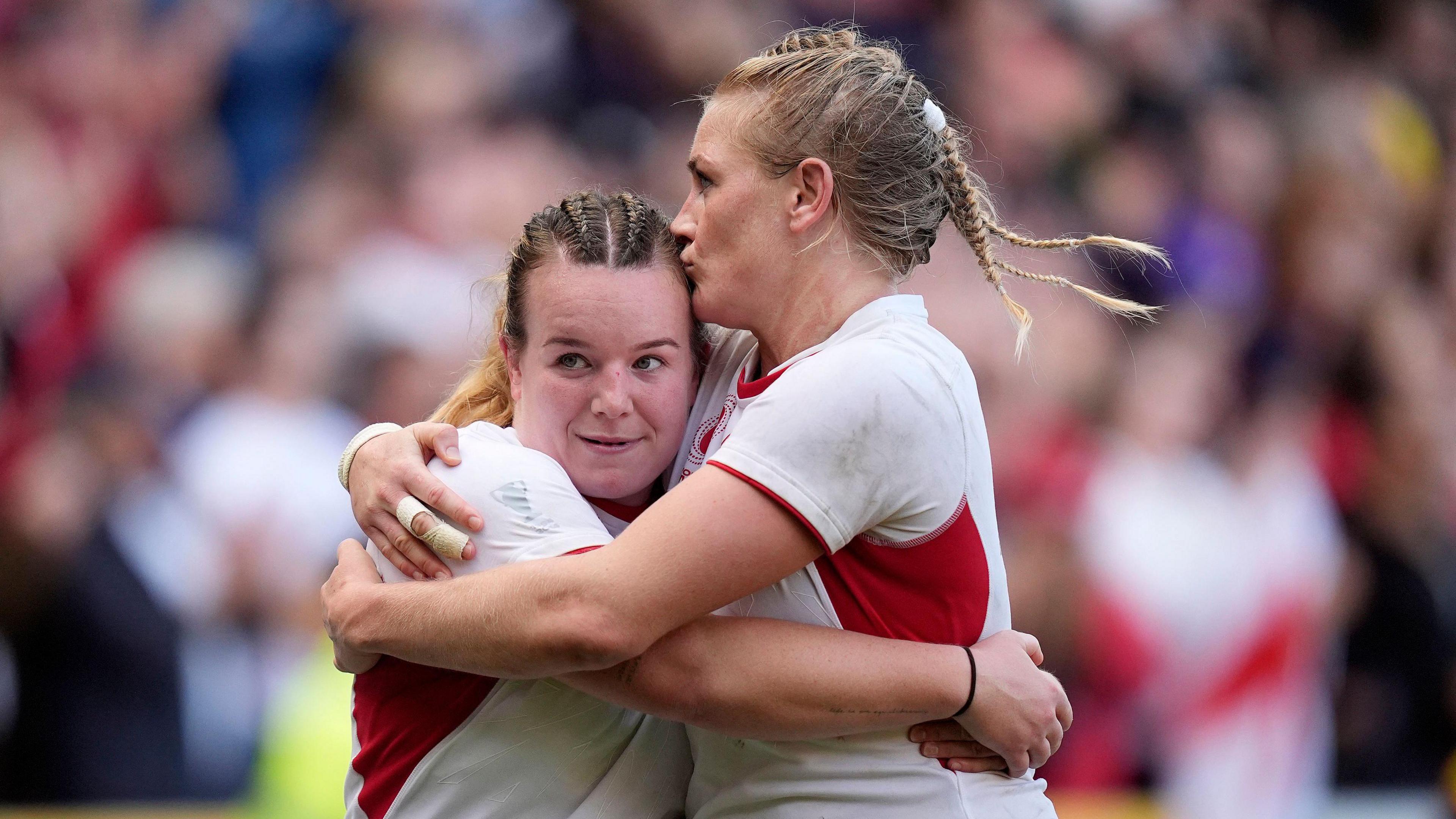 England's Lark Atkin-Davies (left) and Alex Matthews (right) celebrate after the Women's Rugby World Cup 2025 semi-final match at Ashton Gate, Bristol, on 20 September. The two women have their arms around each other and Matthews is kissing Atkin-Davies on the side of her head.