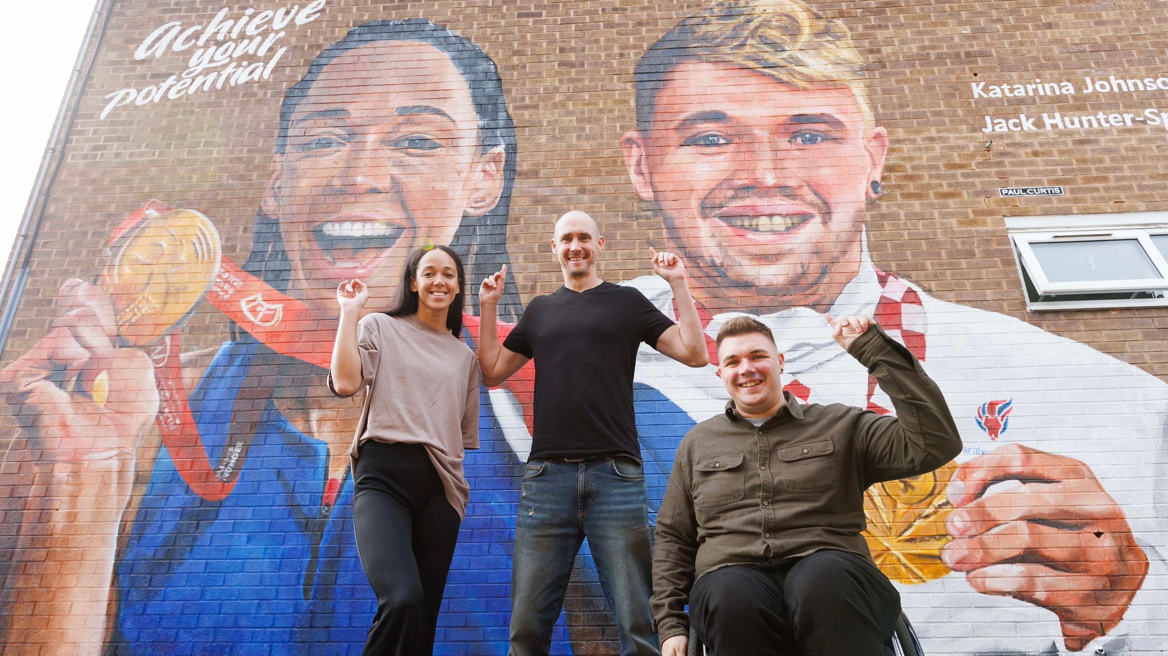 Olympian Katarina Johnson-Thompson, artist Paul Curtis and Paralympian Jack Hunter-Spivey in front of mural in Liverpool