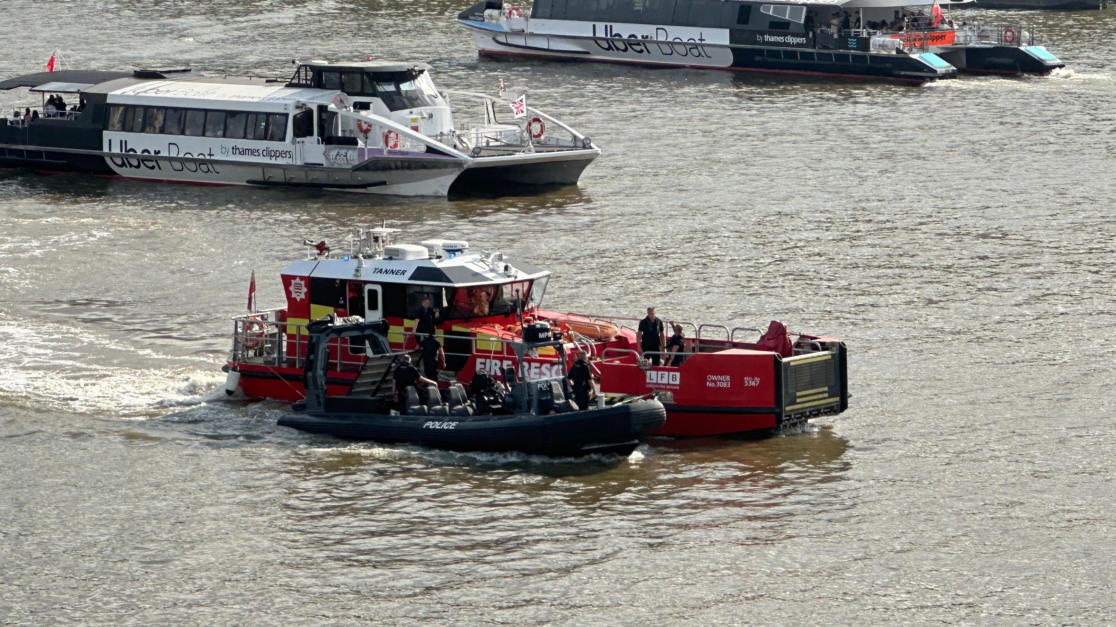 A fire service boat towing a police boat down the Thames.