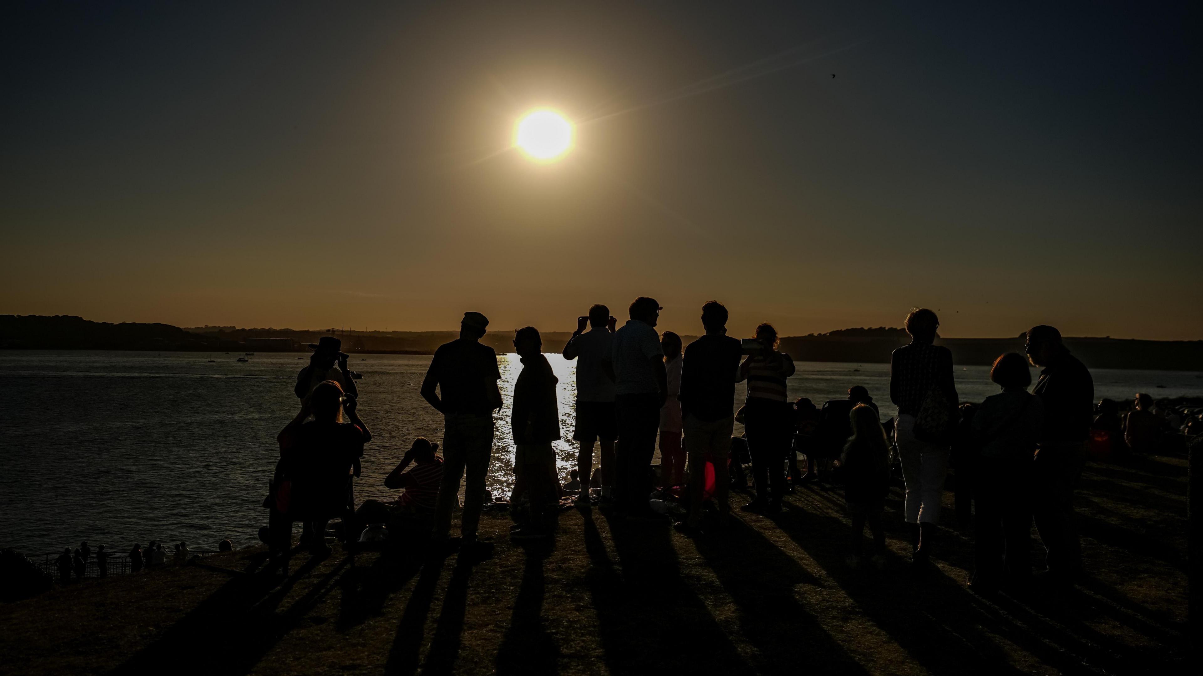 Crowds watch the partial solar eclipse over St Mawes Castle in Cornwall.