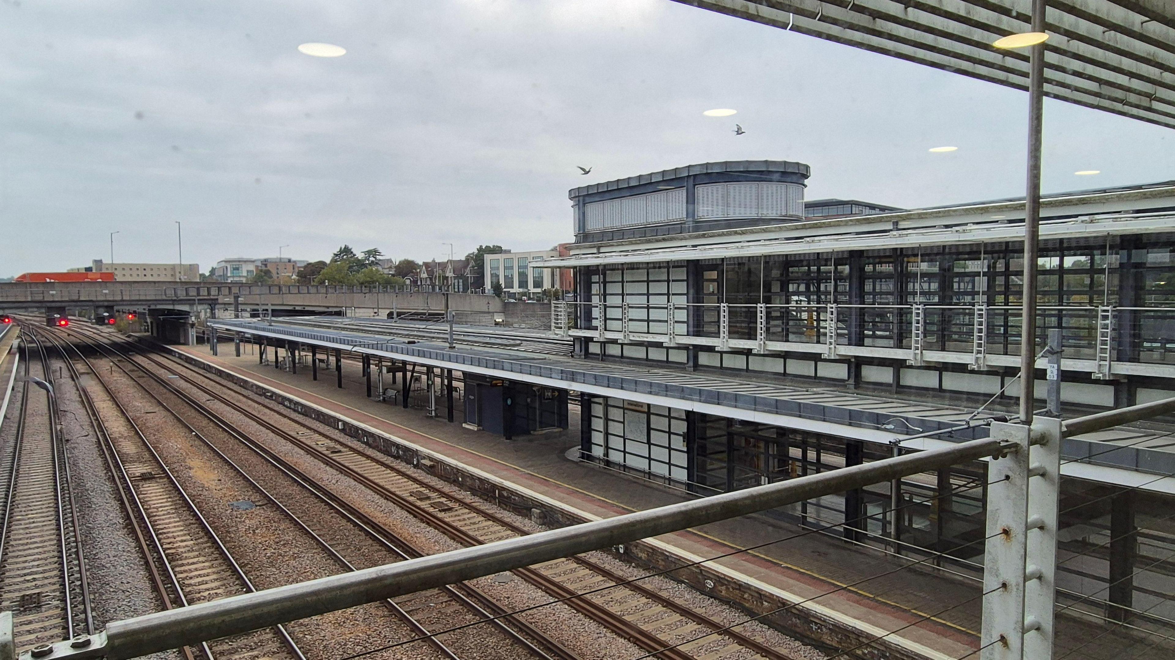 Four sections of standard gauge track standing empty, beside an empty platform at Ashford International Station