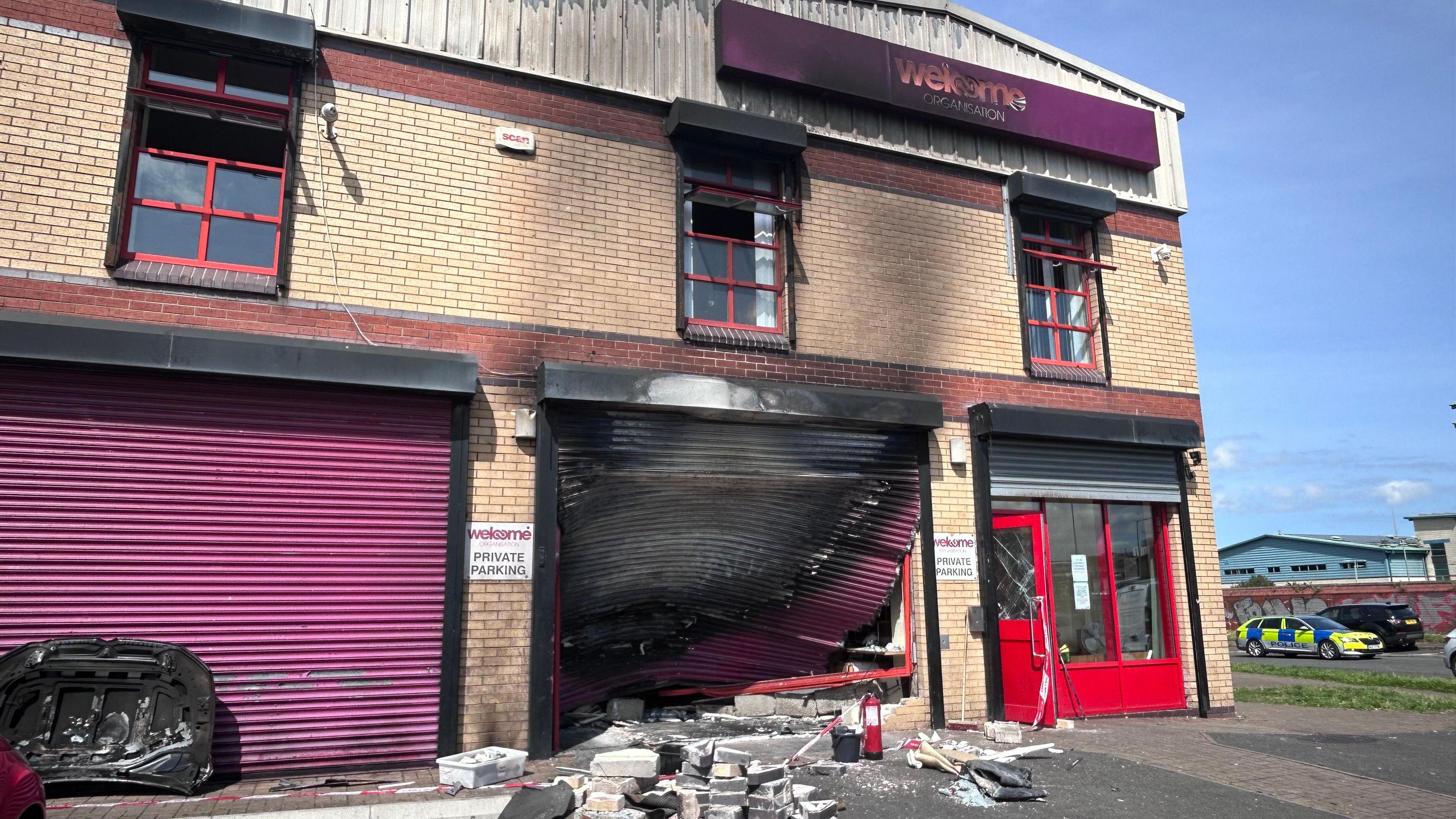 The exterior of the welcome centre shows burn damage to the rolling door, windows and building sign