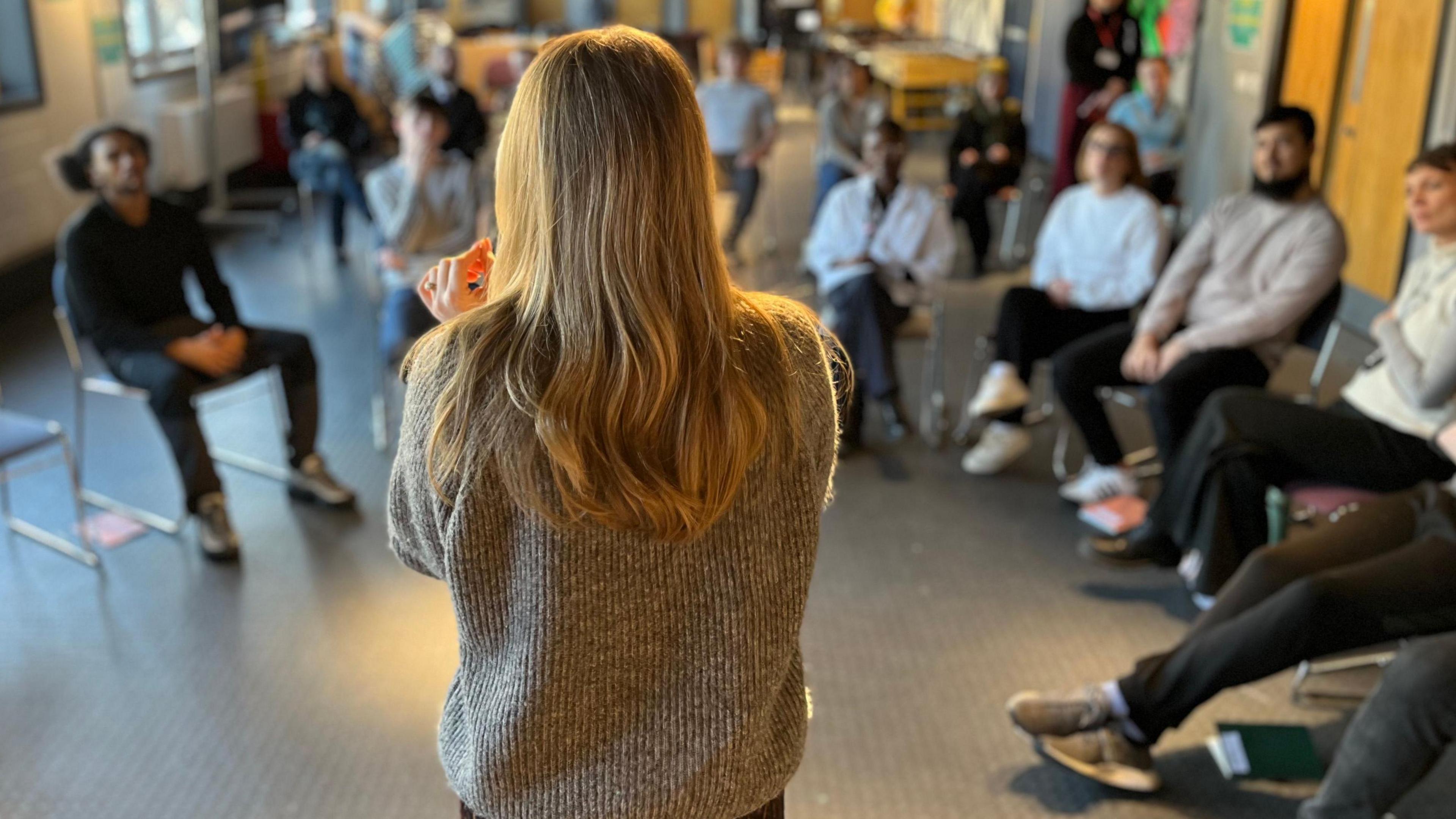 A group of young people who are not in education, employment or training sit in a semicircle during a group coaching session on employability skills. 