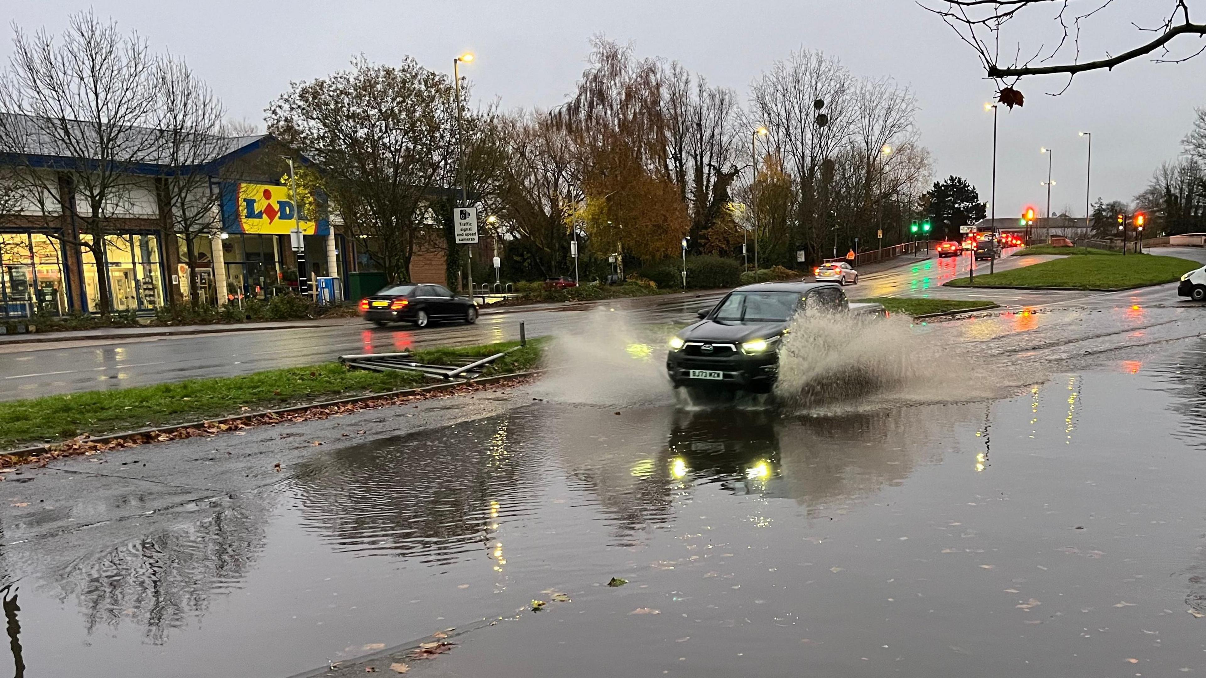 A car driving through a large puddle outside a Lidl store