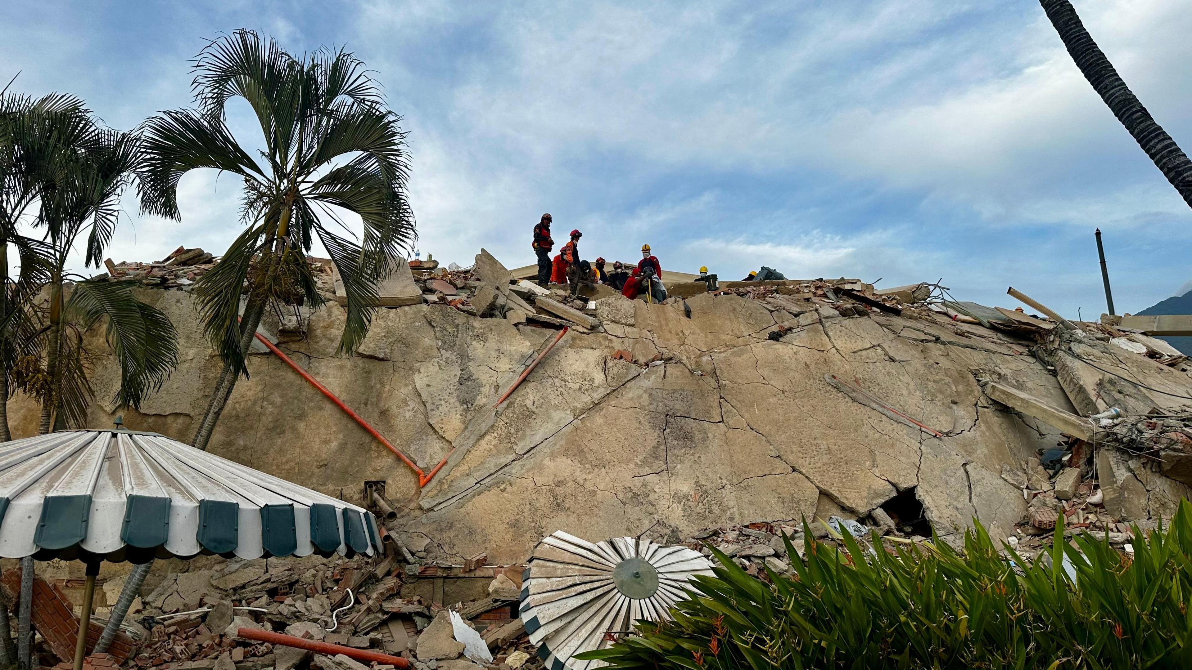 Debris piles up at the Caribe residential complex in the Caraballeda parish, La Guaira state. A small group of rescuers can be seen at the top the pile of rubble.