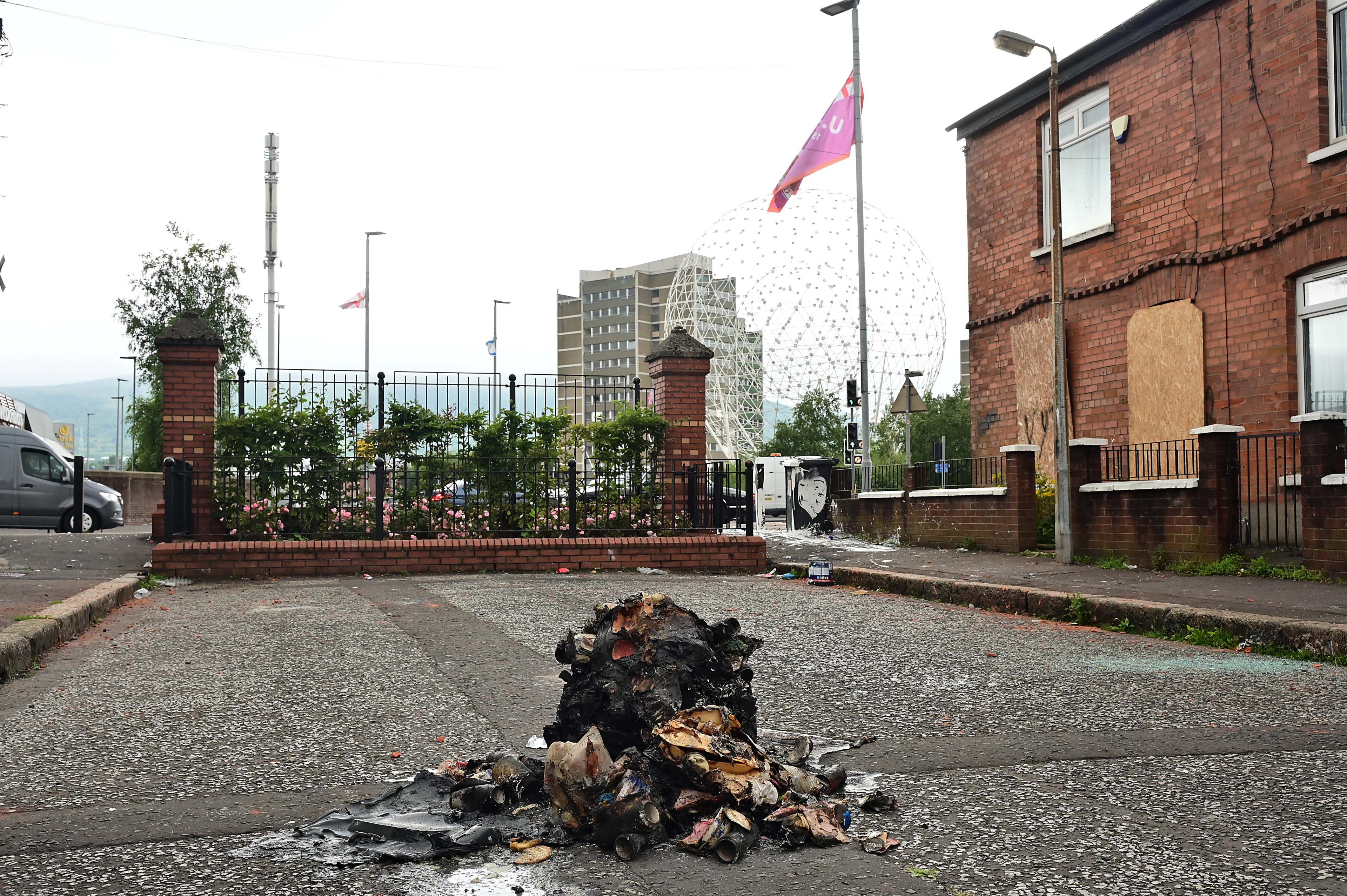 Remains of a fire on the street with Belfast flats and Rise sculpture in background