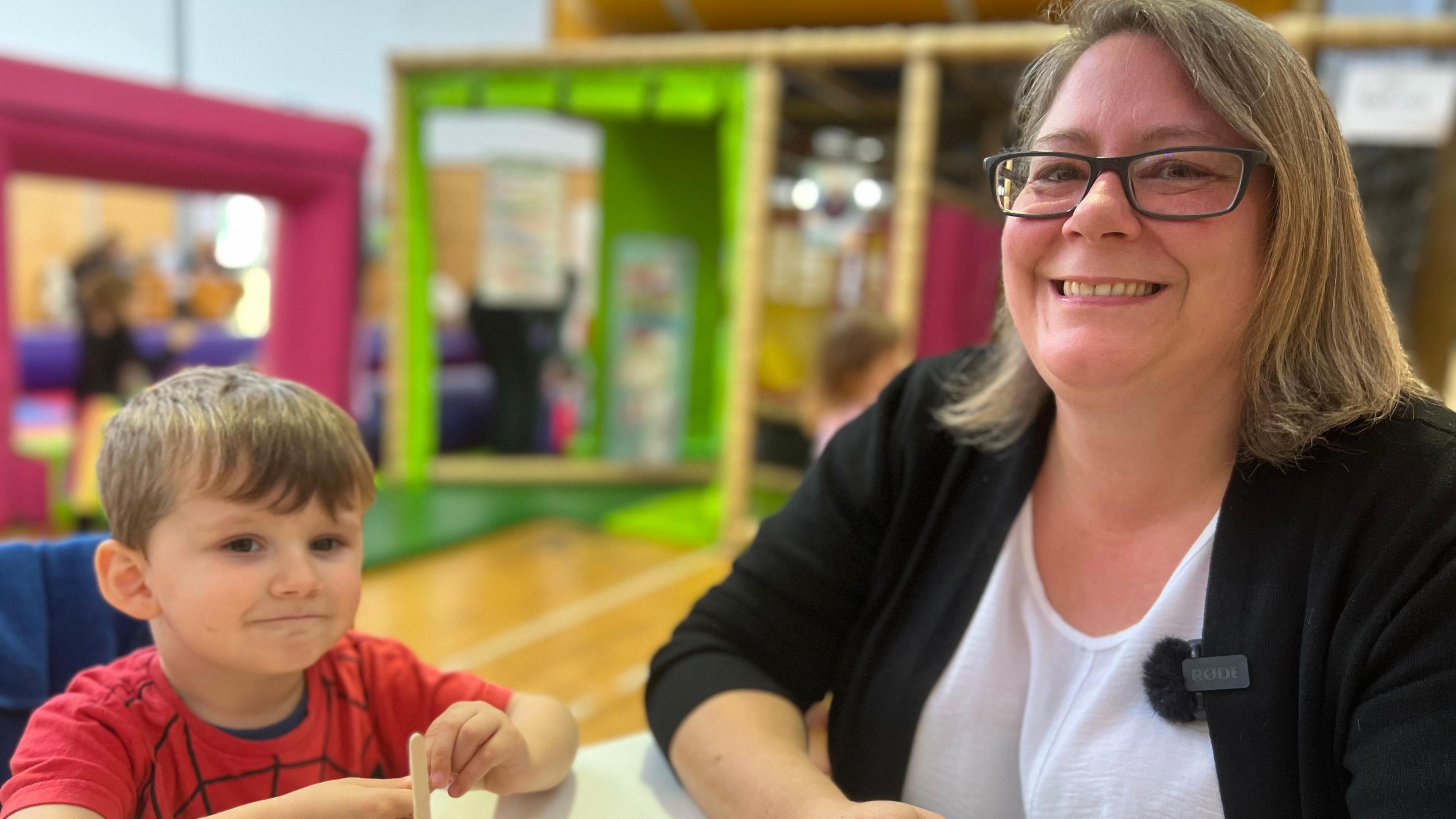 A lady smiles at the camera alongside her young son