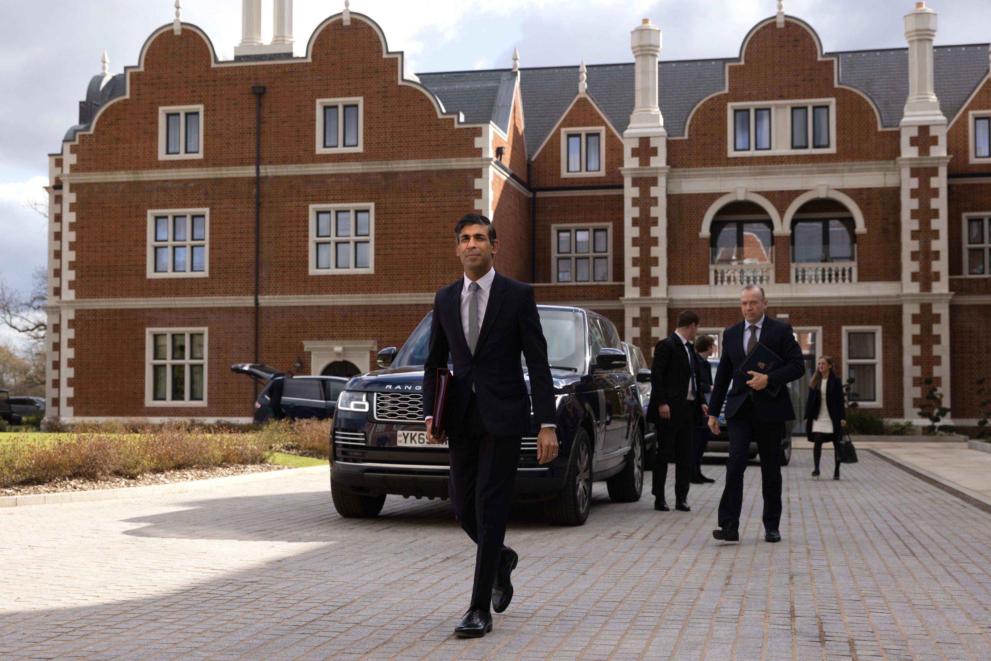 Rishi Sunak walks along a driveway at the Fairmont Windsor Park Hotel