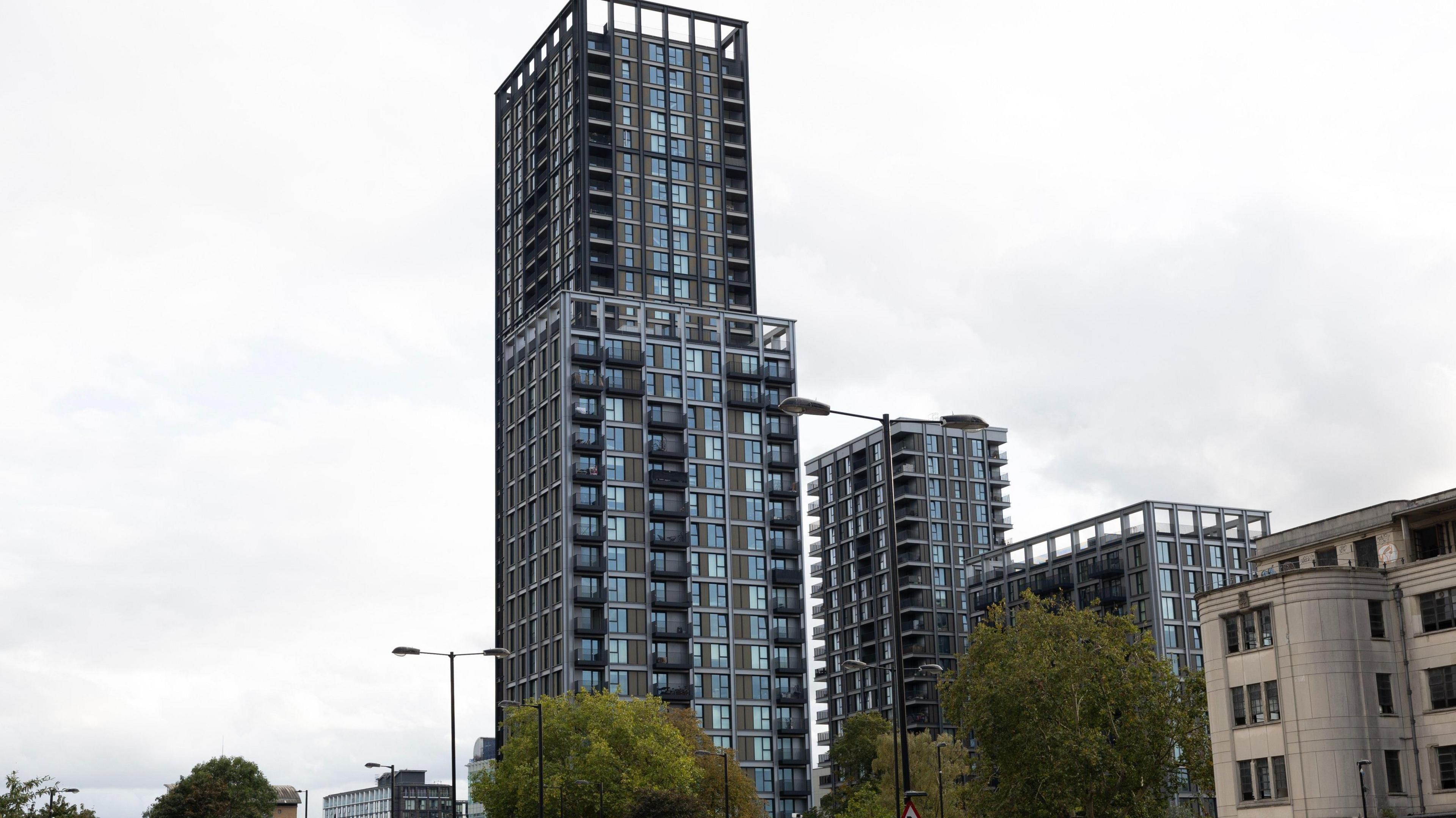 The Fold is seen as a modern glass and steel tower block in Croydon with balconies, photographed from street level.