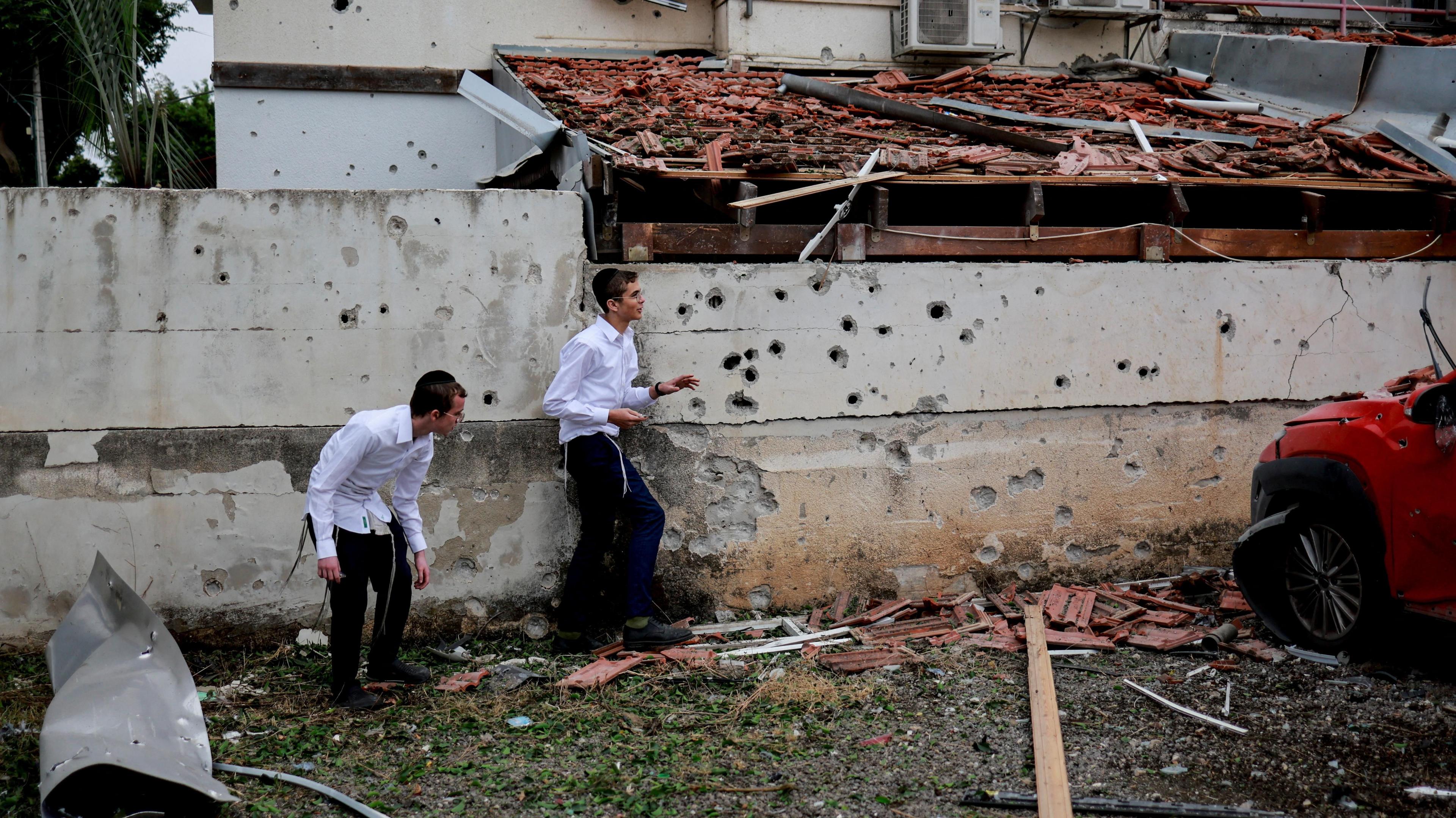 Boys walk at the scene of a Hezbollah rocket attack in Petah Tikva, Israel (24 November 2024)