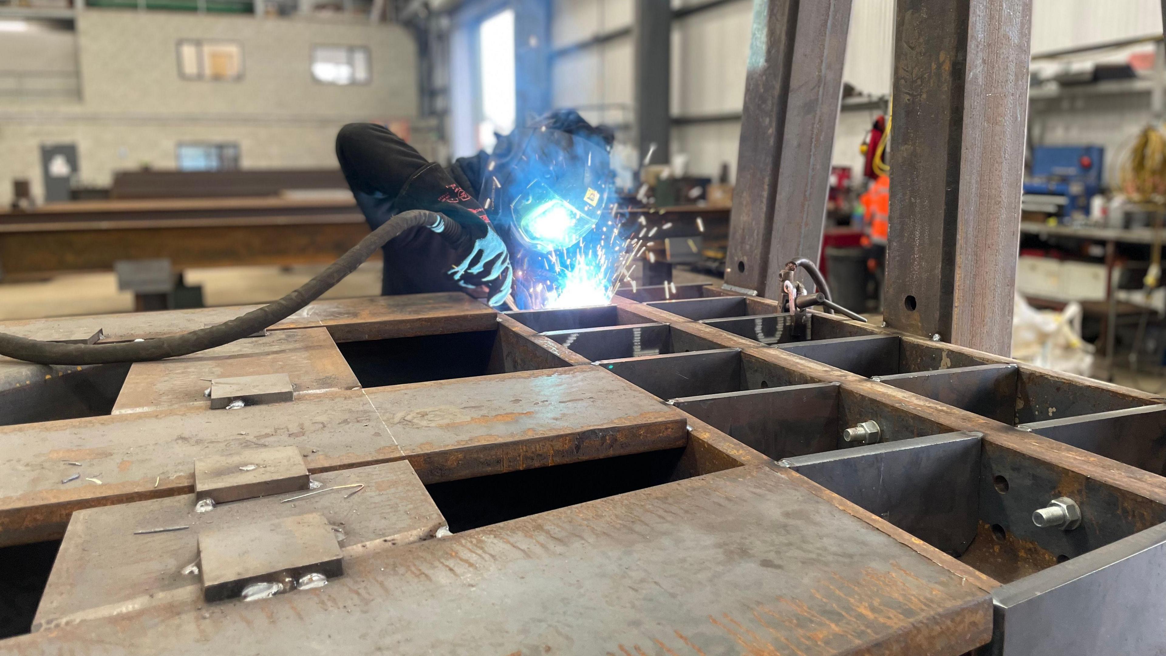 A welder works on a steel section of the Lancaster bomber sculpture