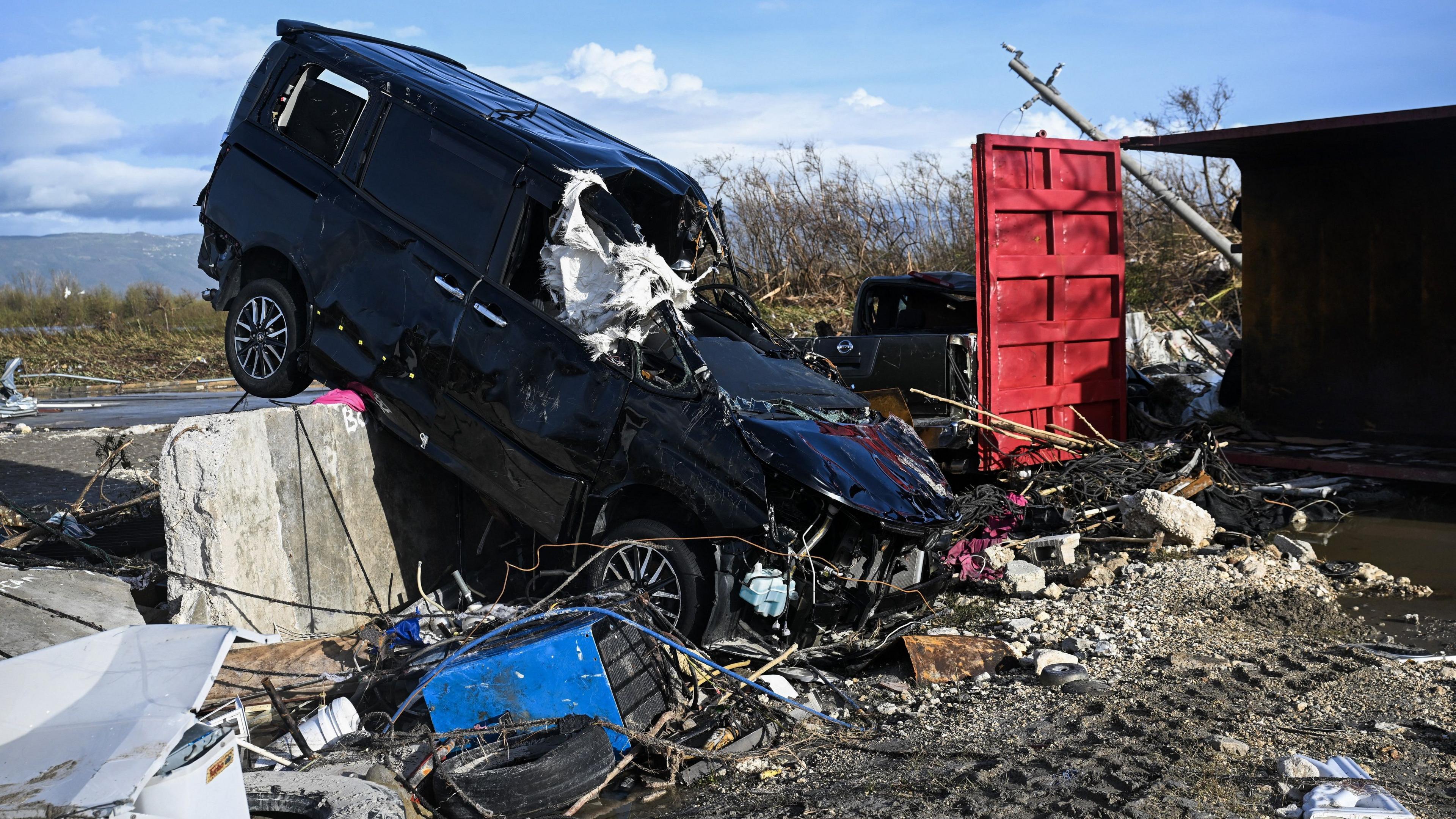 A battered car juts out of debris from Hurricane Melissa. 