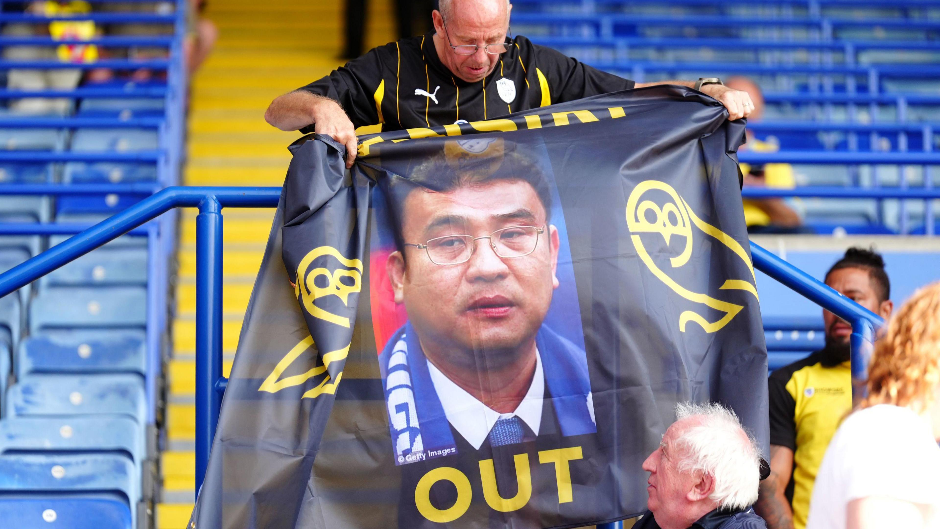 a fan holding a flag angry at Dejphon Chansiri