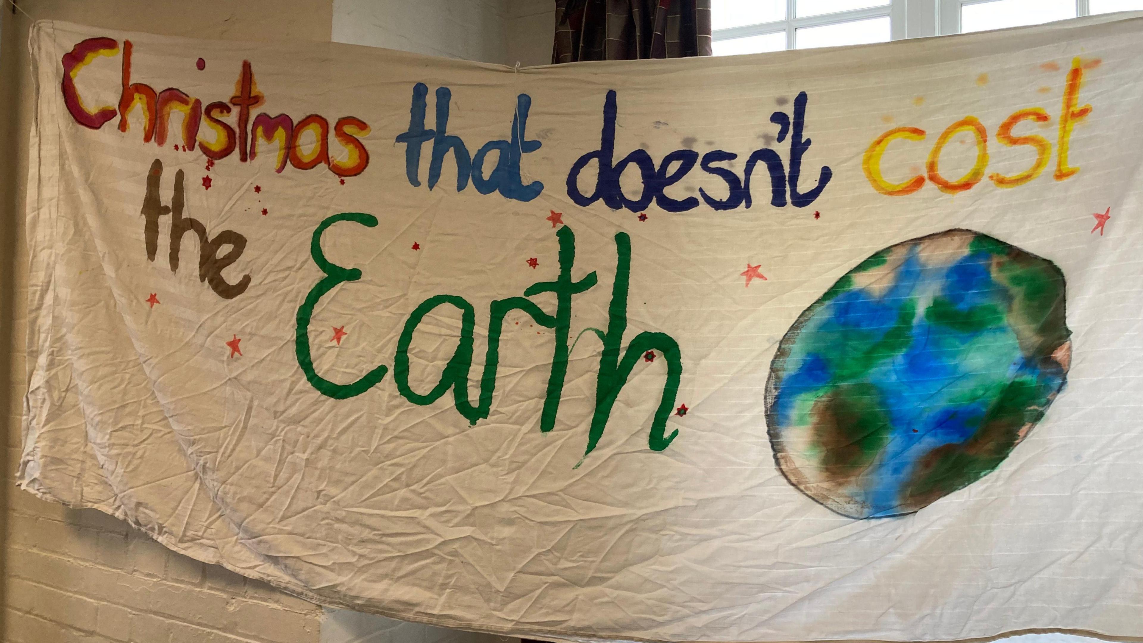 Hand-painted flag fabric with the message "Christmas that doesn't cost the earth" and a picture of Earth.