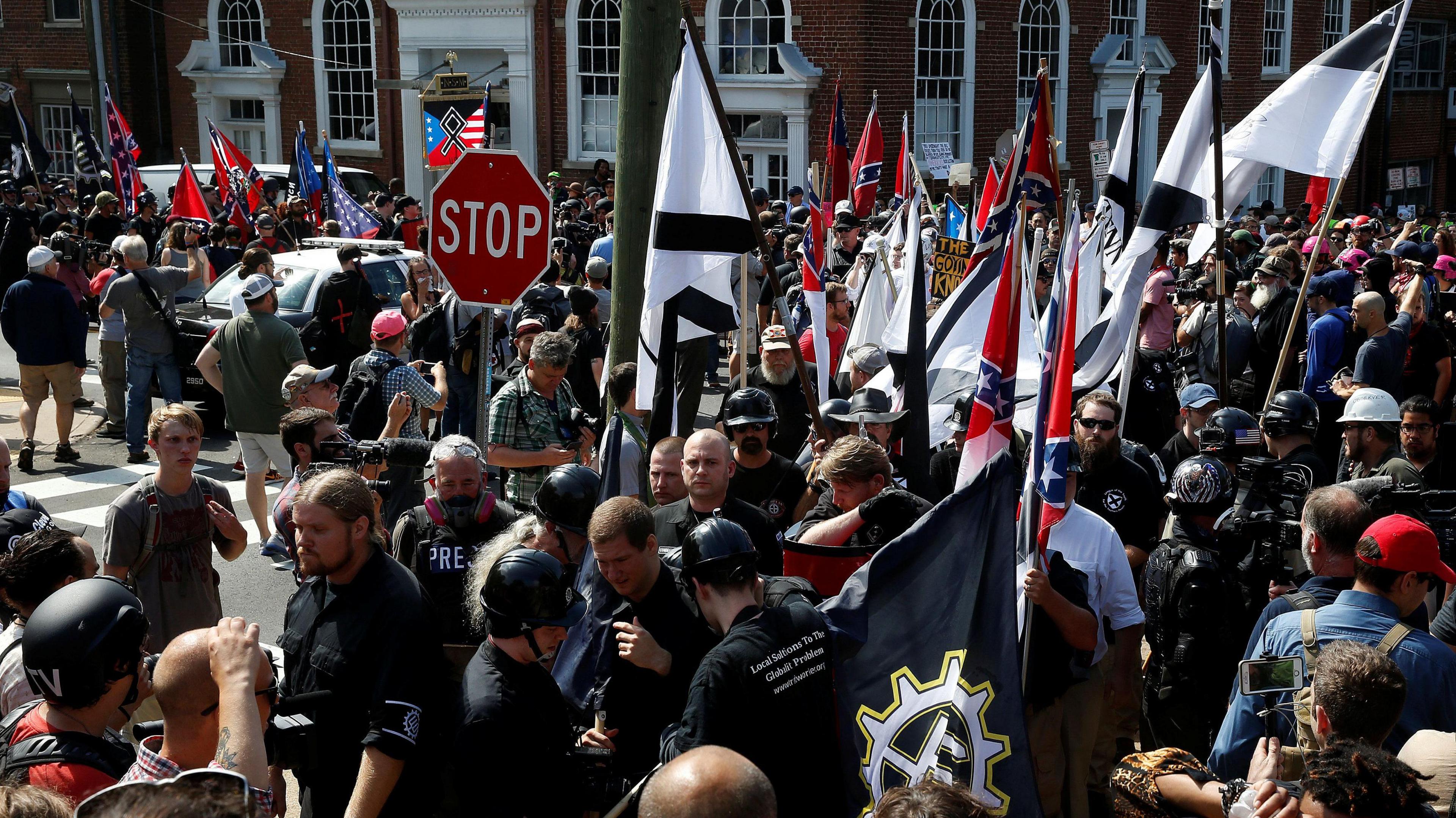 White supremacists, wearing black clothing, Nazi uniforms and helmets, rally in Charlottesville, Virginia in 2017, while carrying Confederate and black and white flags