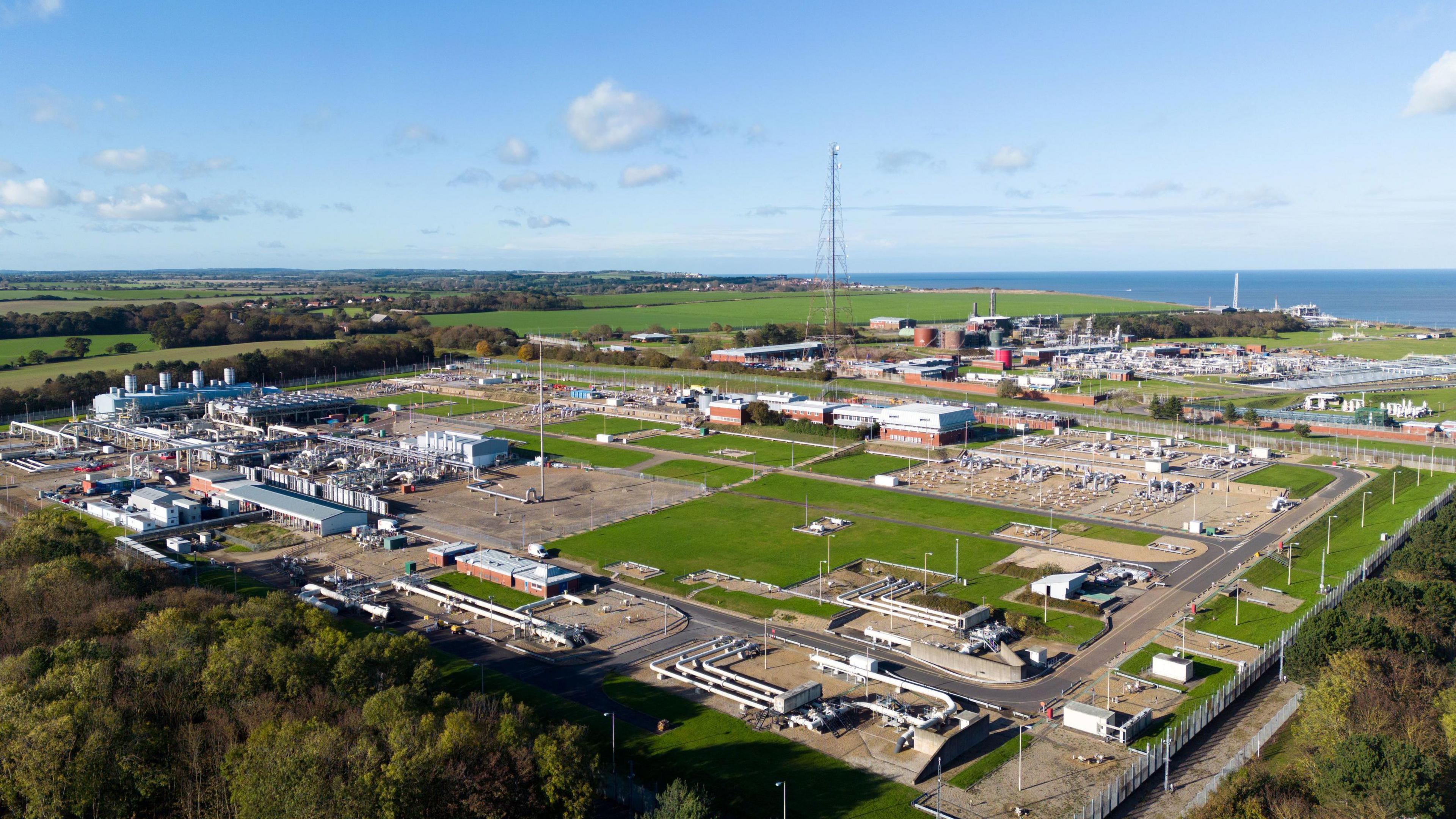 A wider view from the air of the Bacton Gas Terminal - it's a large industrial site with the North Sea in the background.