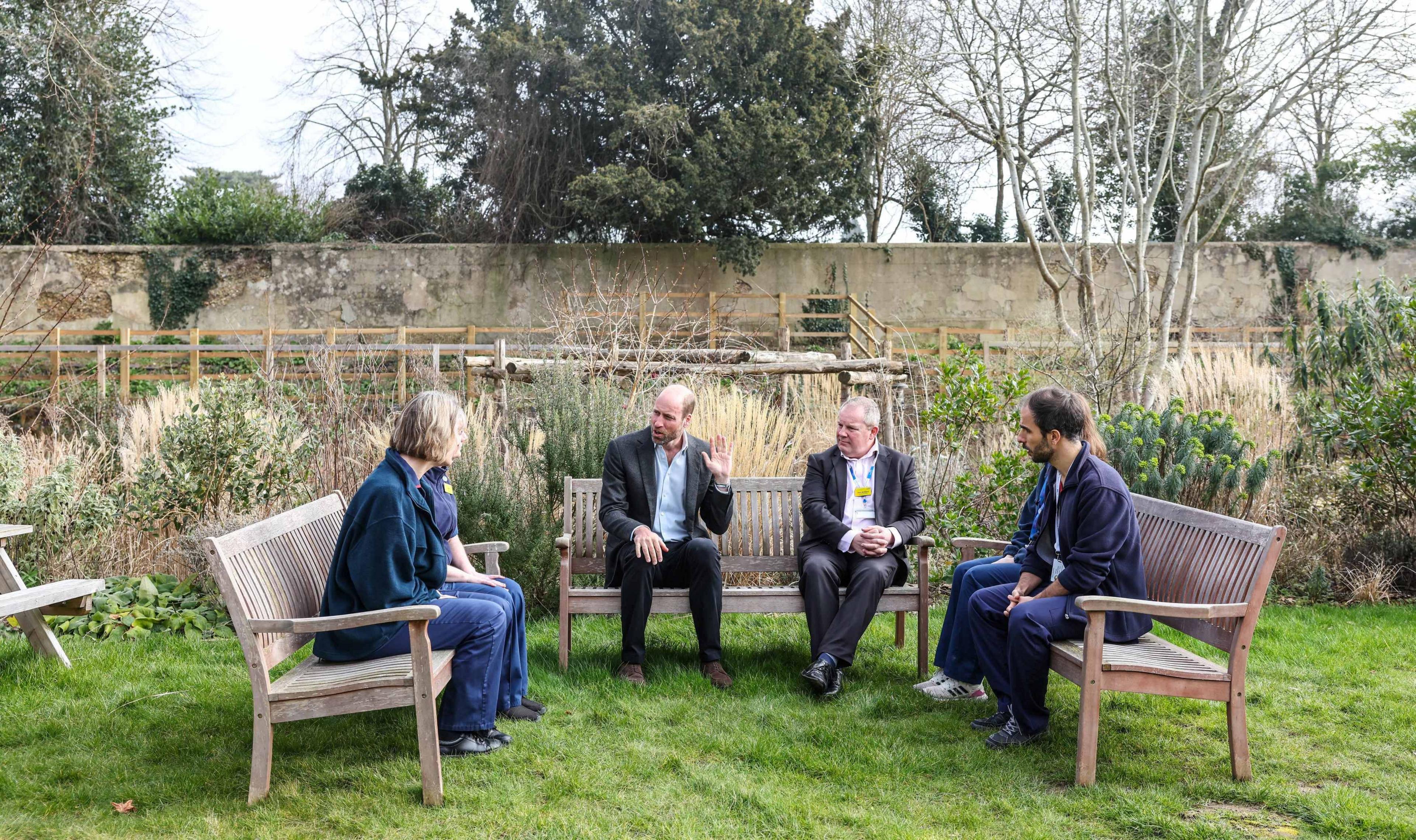 Prince William sitting on a bench with five other people (NHS Staff) talking about their work on the frontline.