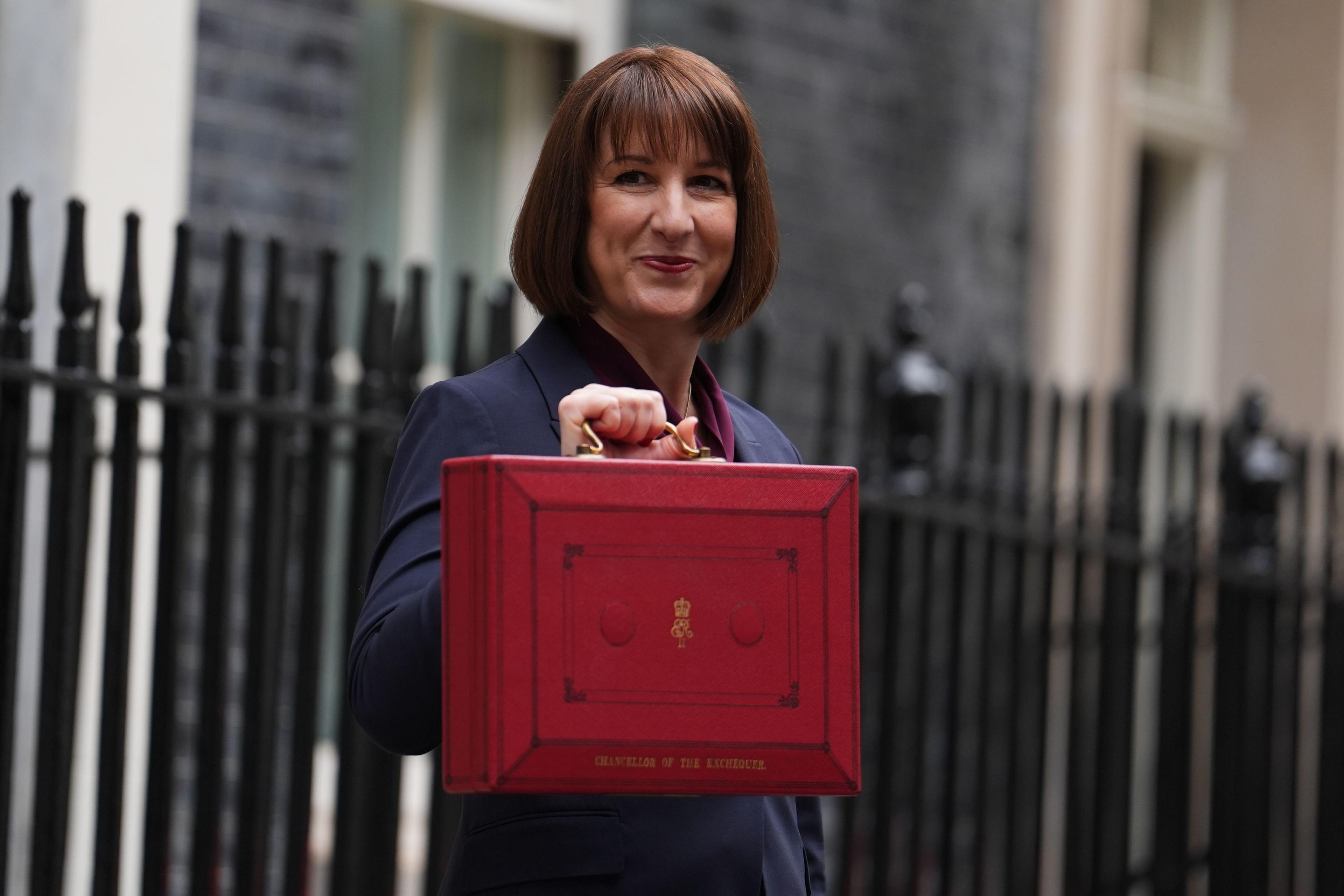 Chancellor of the Exchequer, Rachel Reeves holding up. red budget box in Downing Street