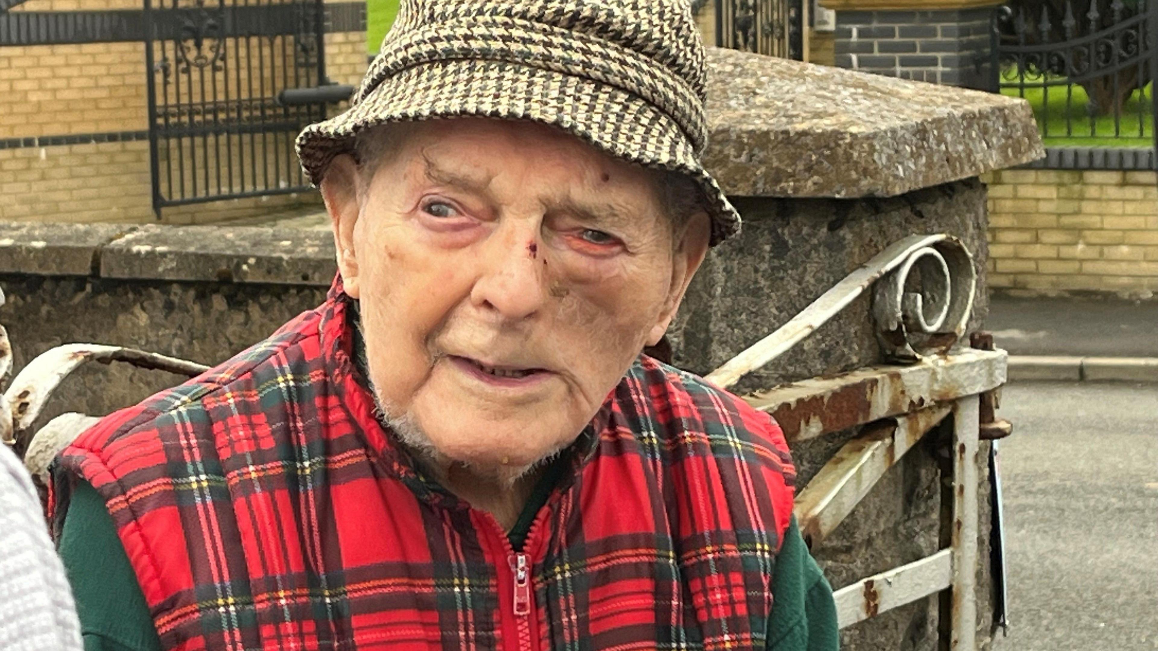 Basil Smith, 103, wearing a houndstooth pattern hat and red checked body warmer