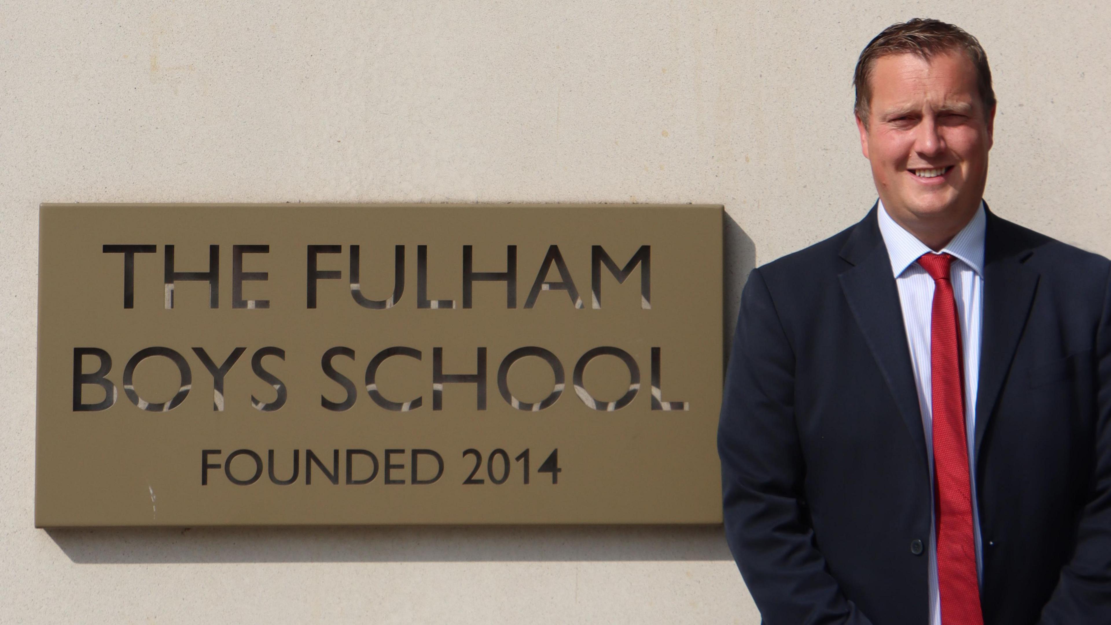 David Smith standing next to The Fulham Boys School sign