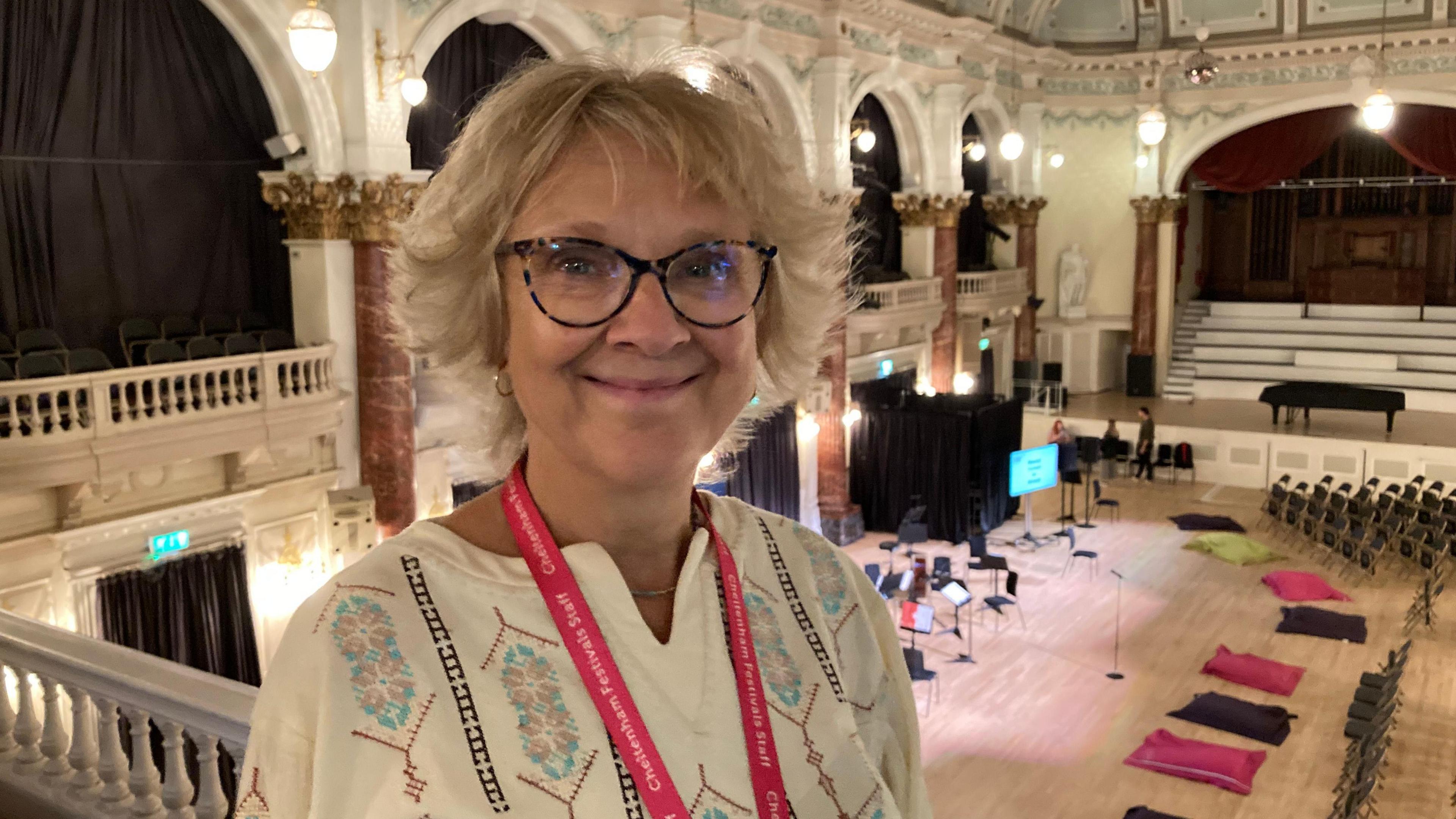 Pip Claridge, Cheltenham Festivals partnership co-ordinator, wearing white top and standing near upper seating at concert hall.