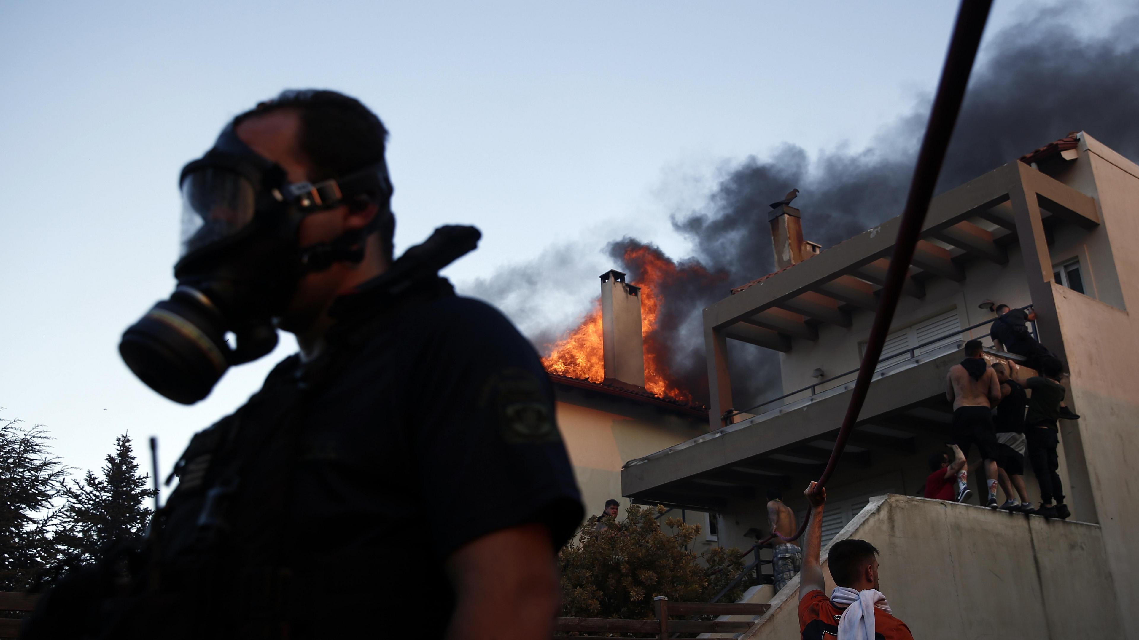 Volunteers battle to put out a fire burning houses in the residential area of Kryoneri, in the suburbs of Athens, Greece