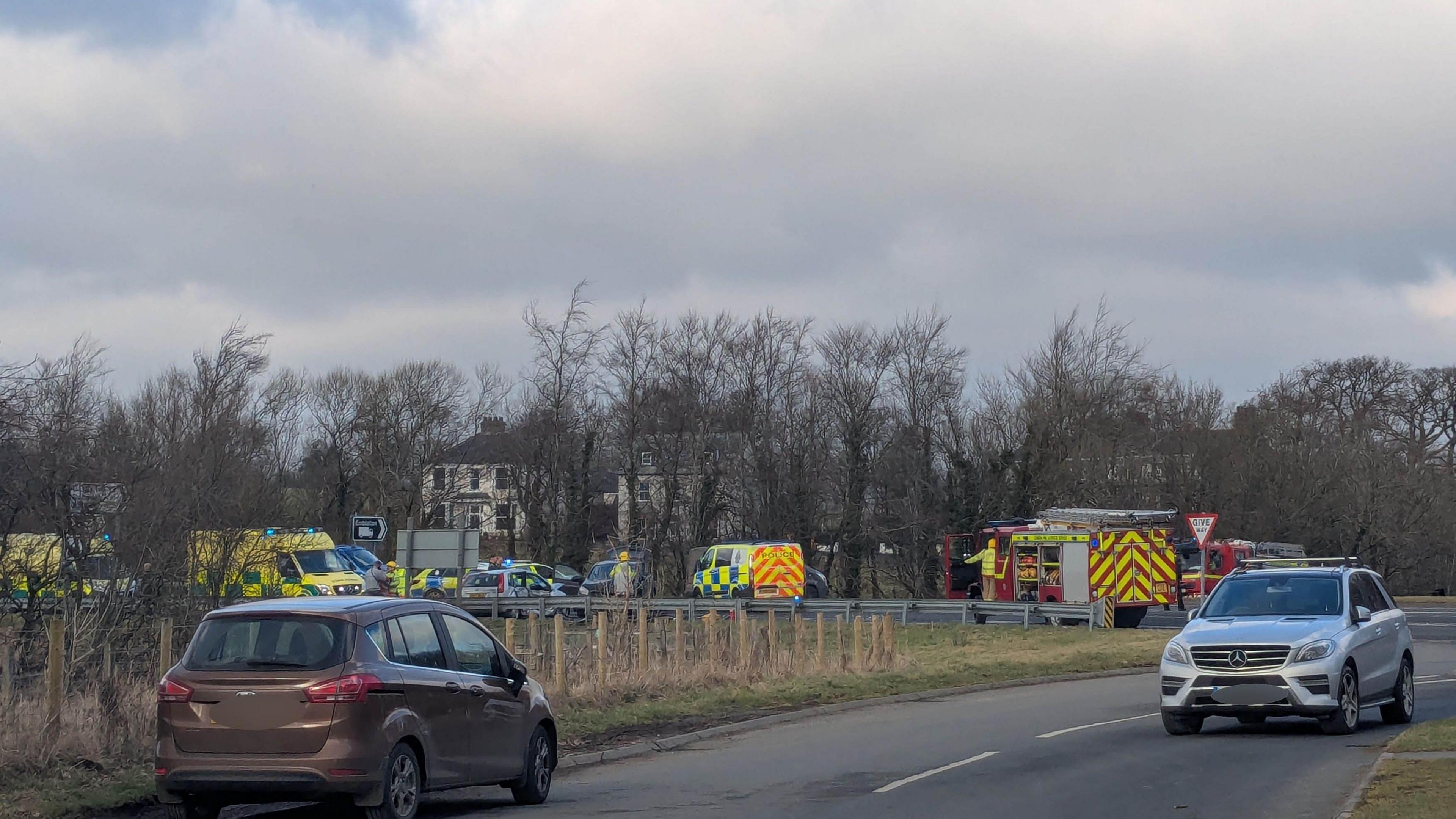 Half a dozen emergency vehicles are parked on a road.