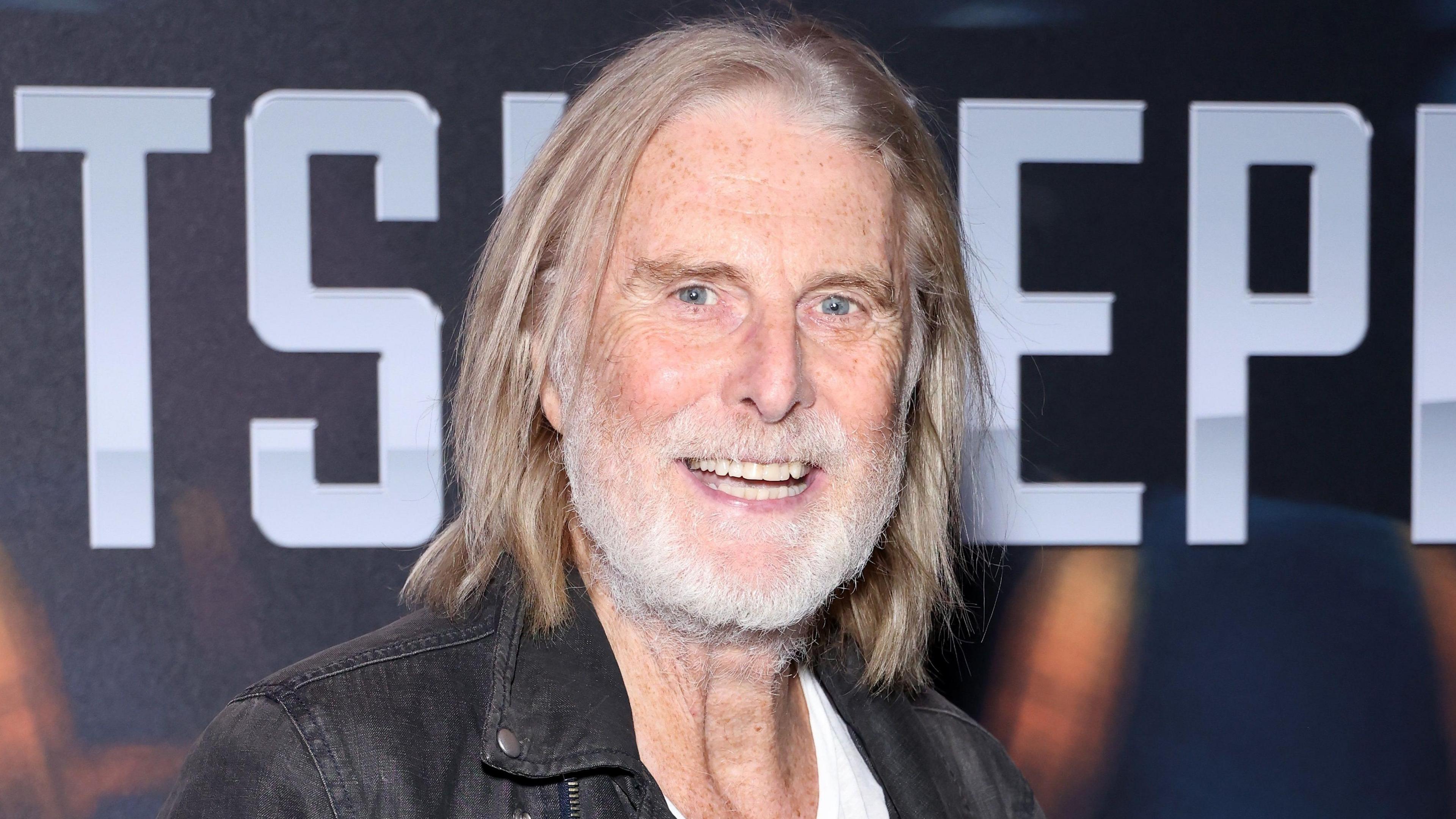 David Threlfall smiling with shoulder-length hair and grey beard