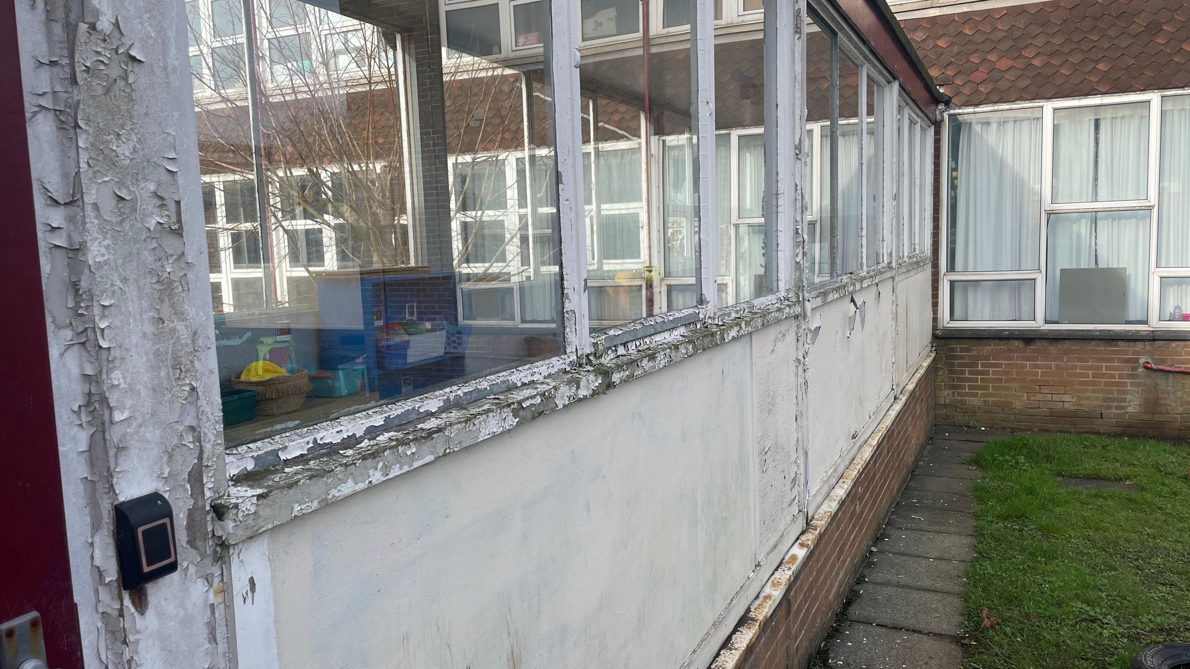 A line of windows on a school building that are rotting and crumbling away.