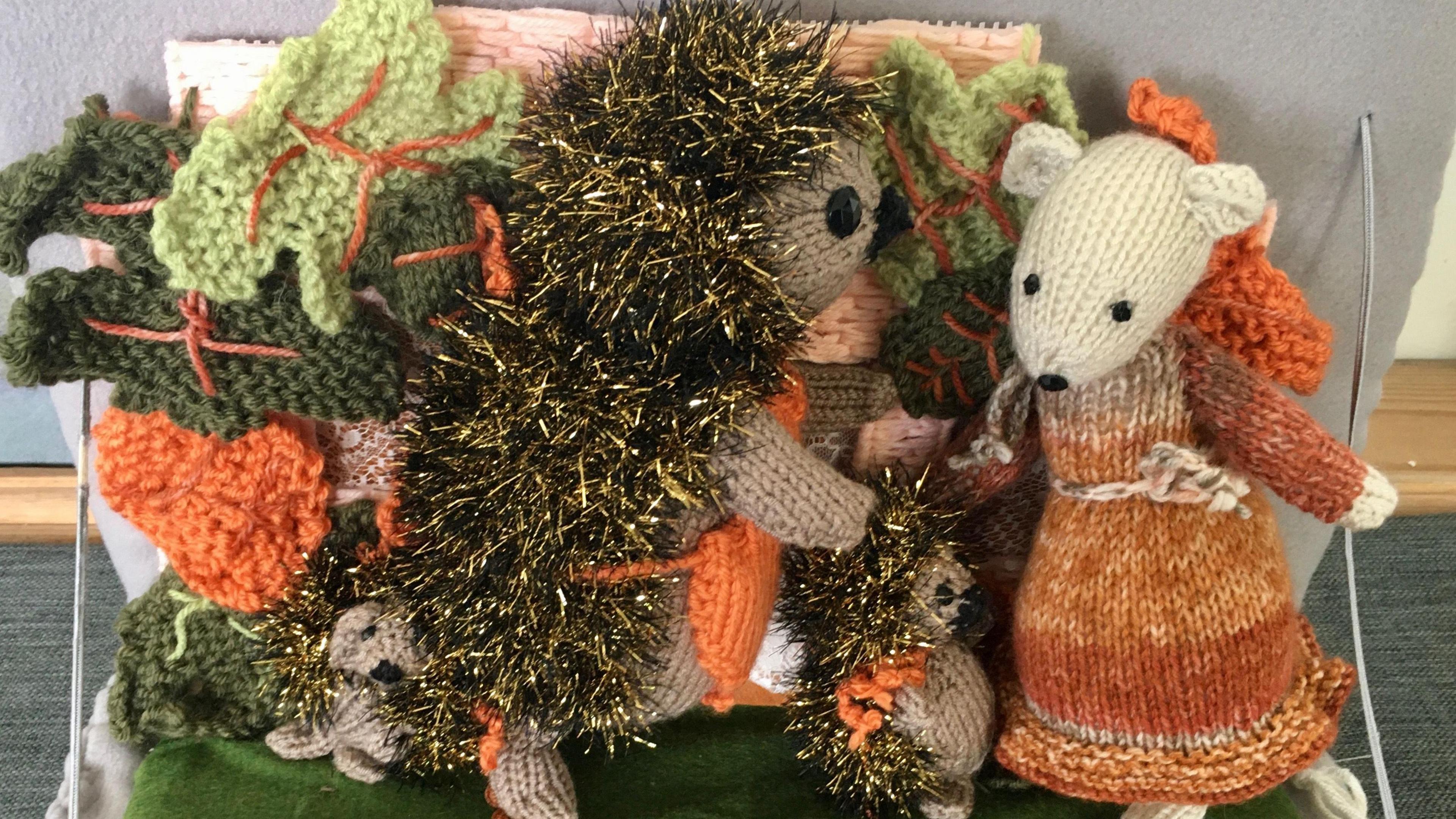 A knitted sparkly hedgehog, with a knitted mouse wearing a dress stood next to it.