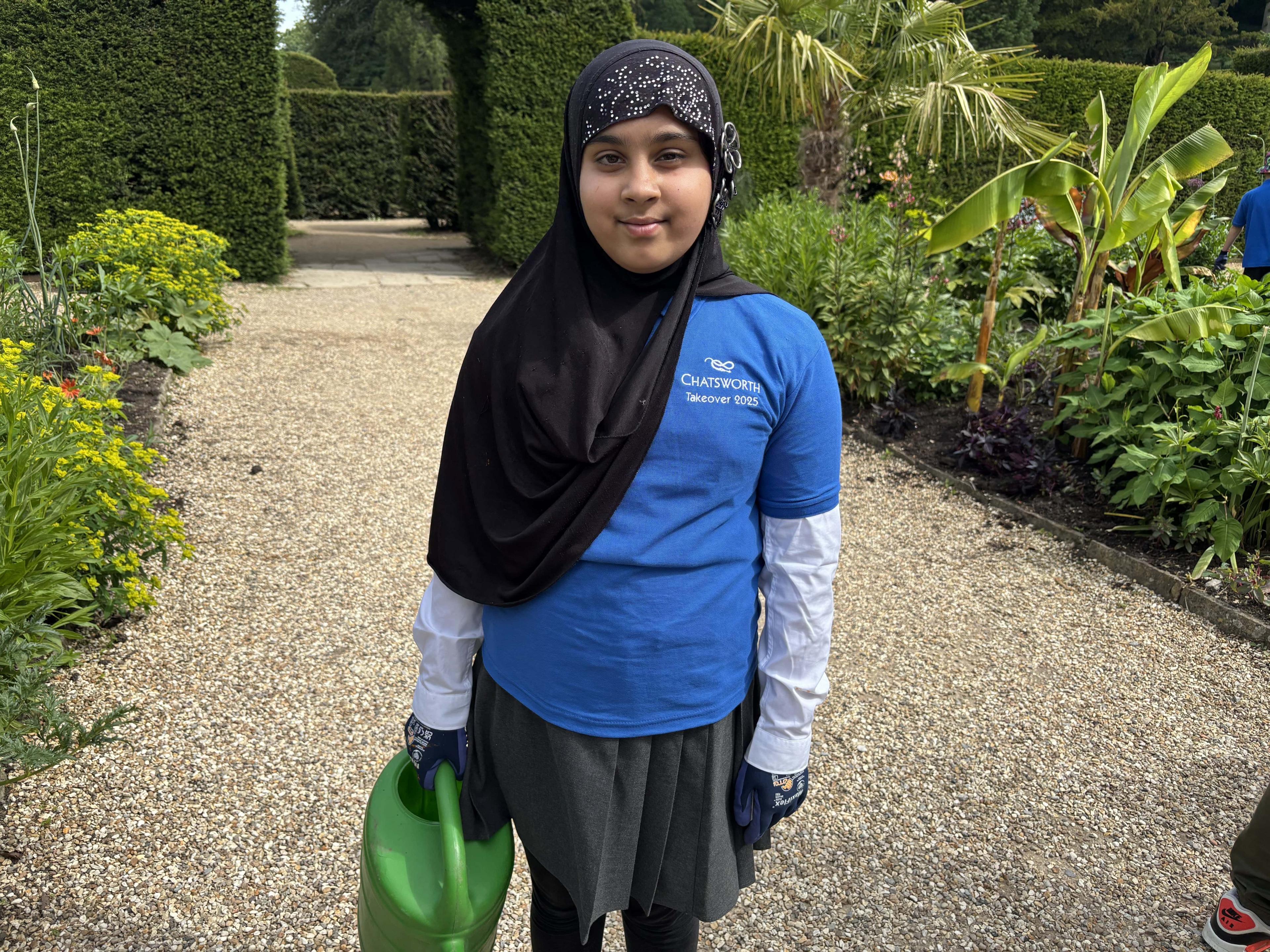 Primary school pupil in gardens of Chatsworth House with watering can.