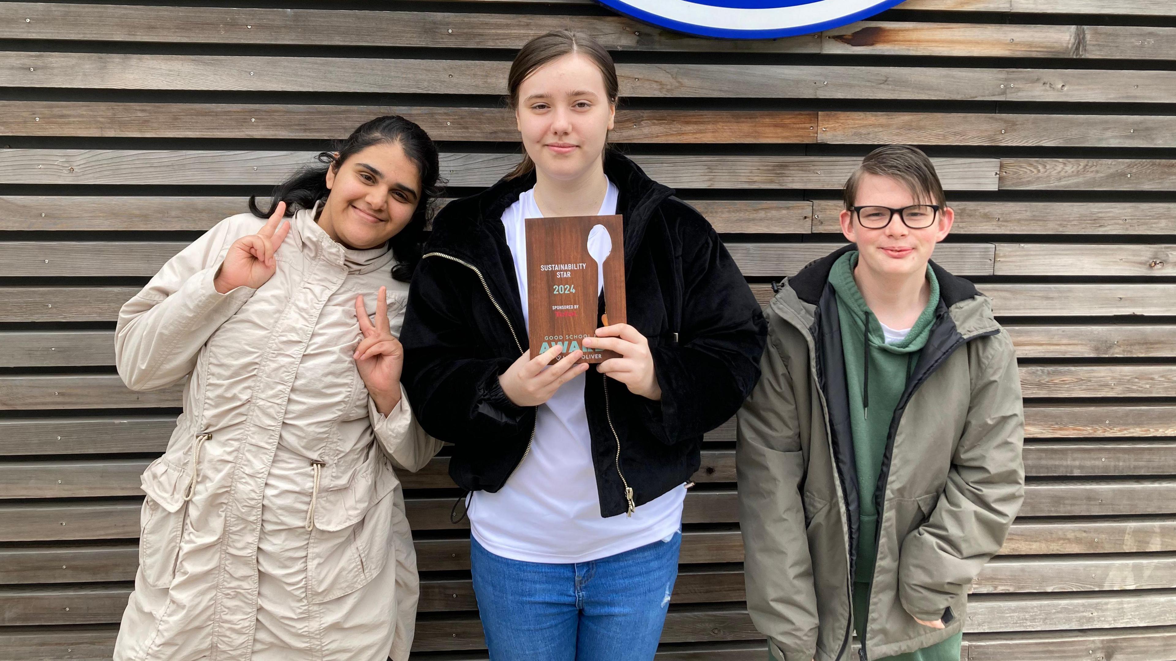 Pupils Radiya, Mercedes and Keiran holding their award and posing for the camera.