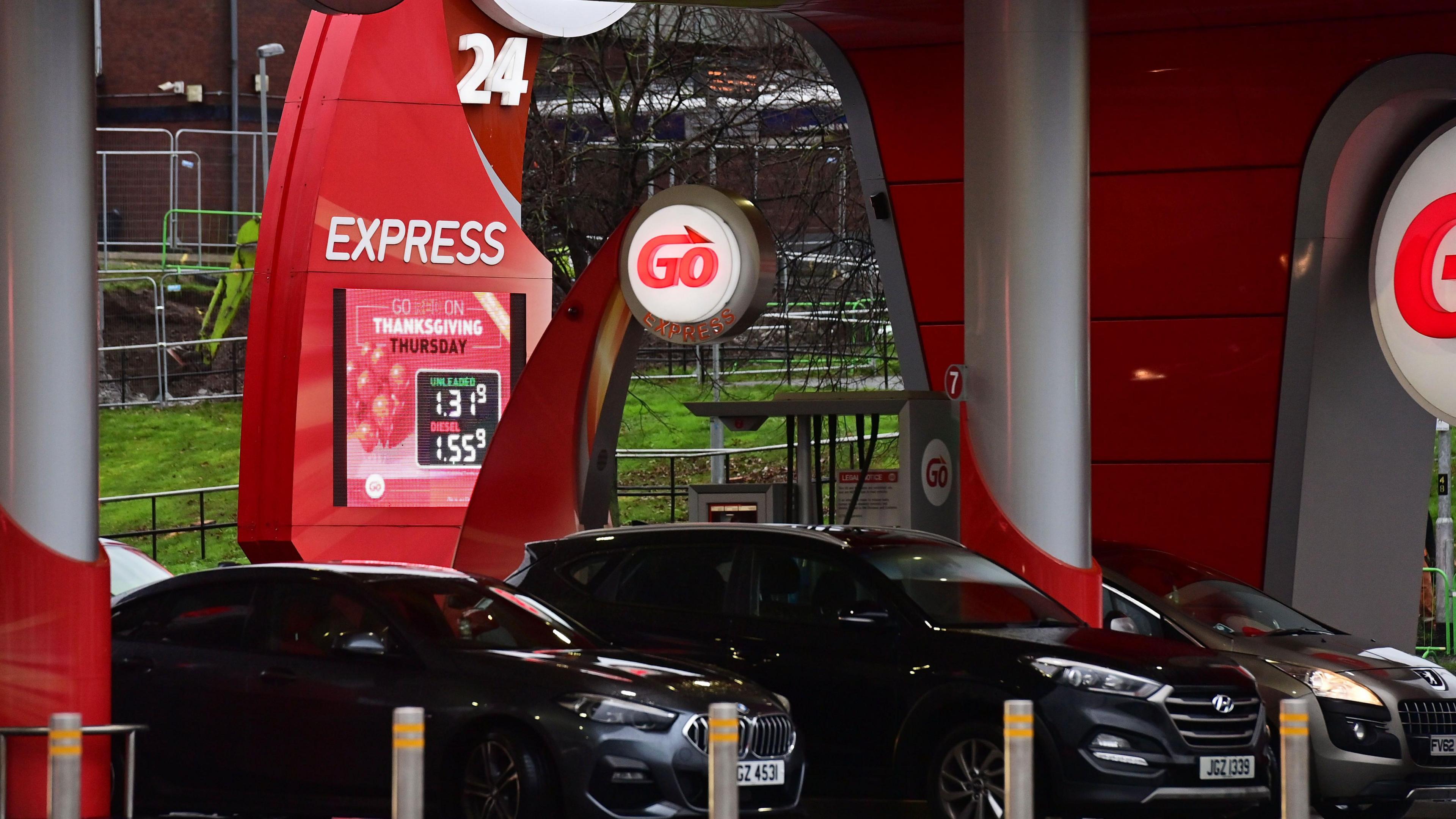 Cars are in a Go petrol station. The Go logo, which is Go in red lettering, is lit up.