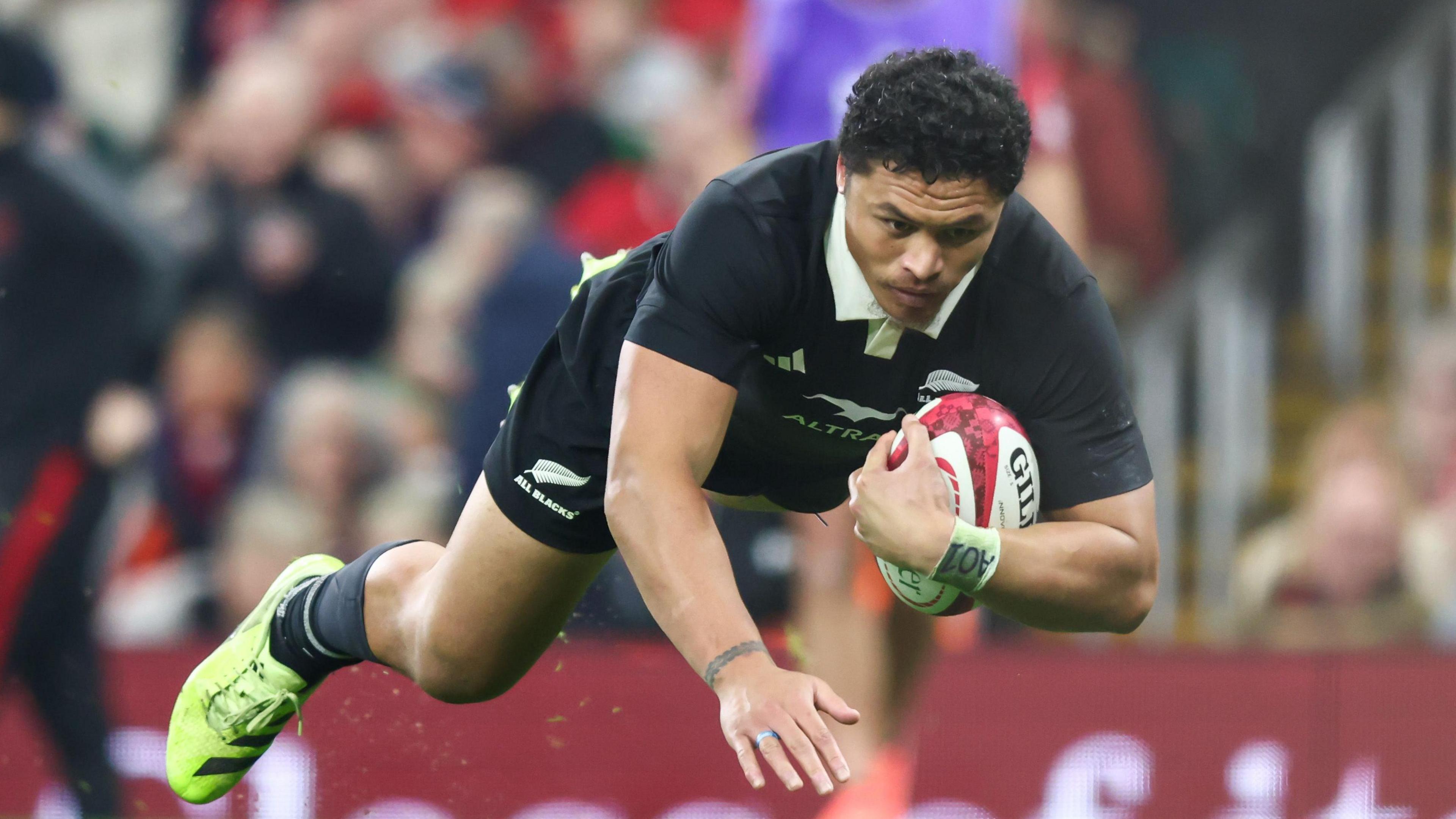 New Zealand wing Caleb Clarke dives with ball under arm to score a try