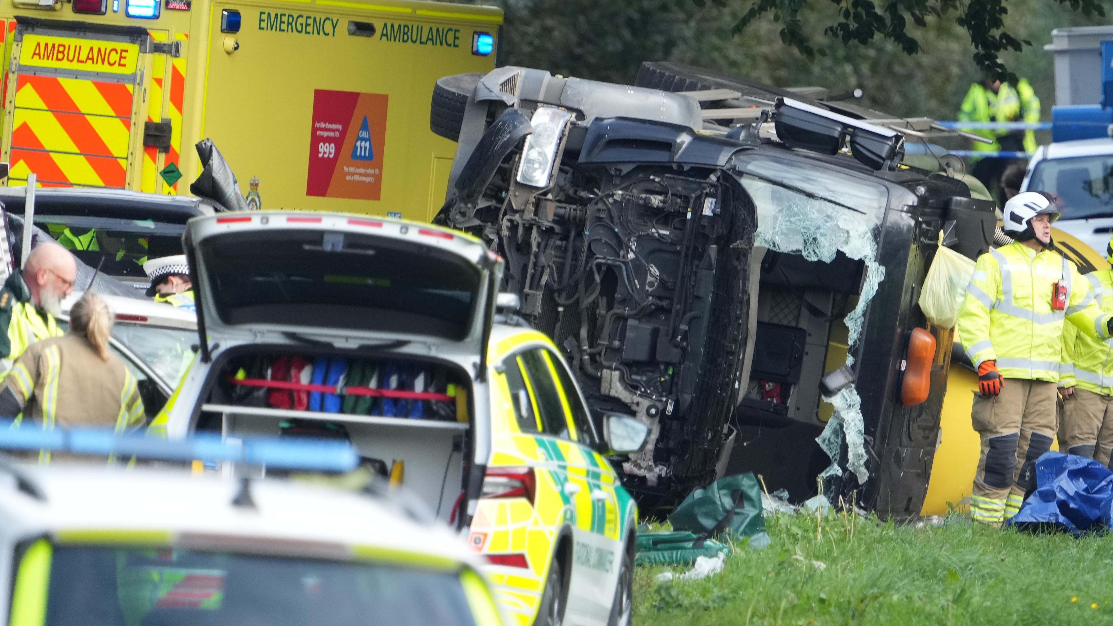 A picture of a number of emergency service vehicles by a lorry that is on its side with a broken windscreen