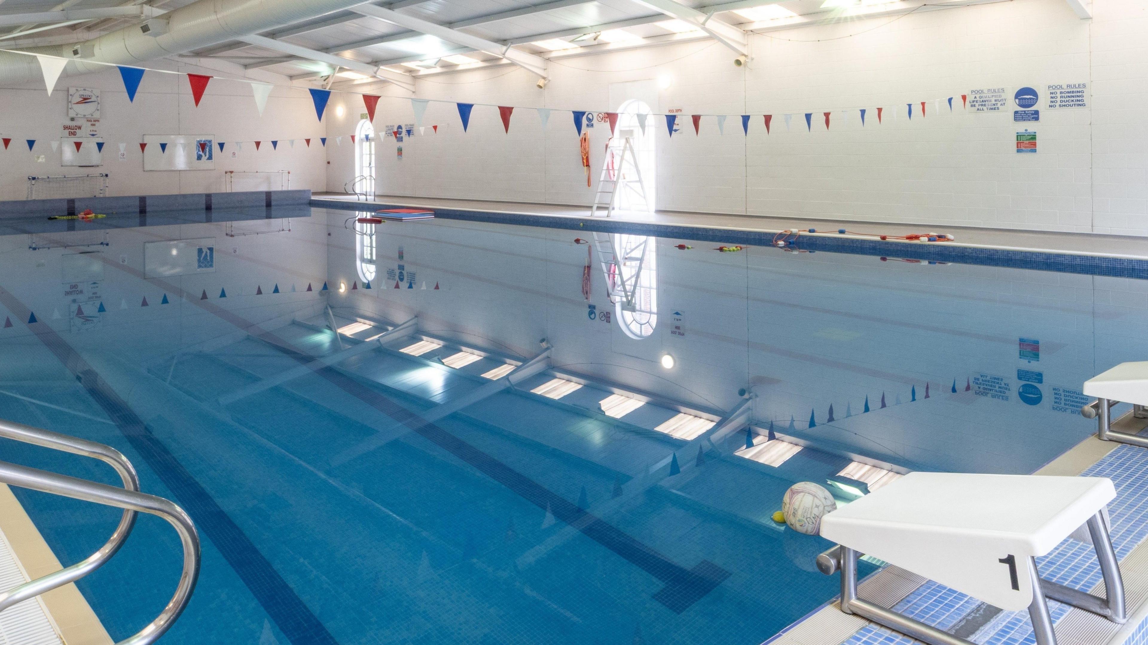 A shot of an empty indoor pool, with white walls and red, white and blue bunting across the ceiling.