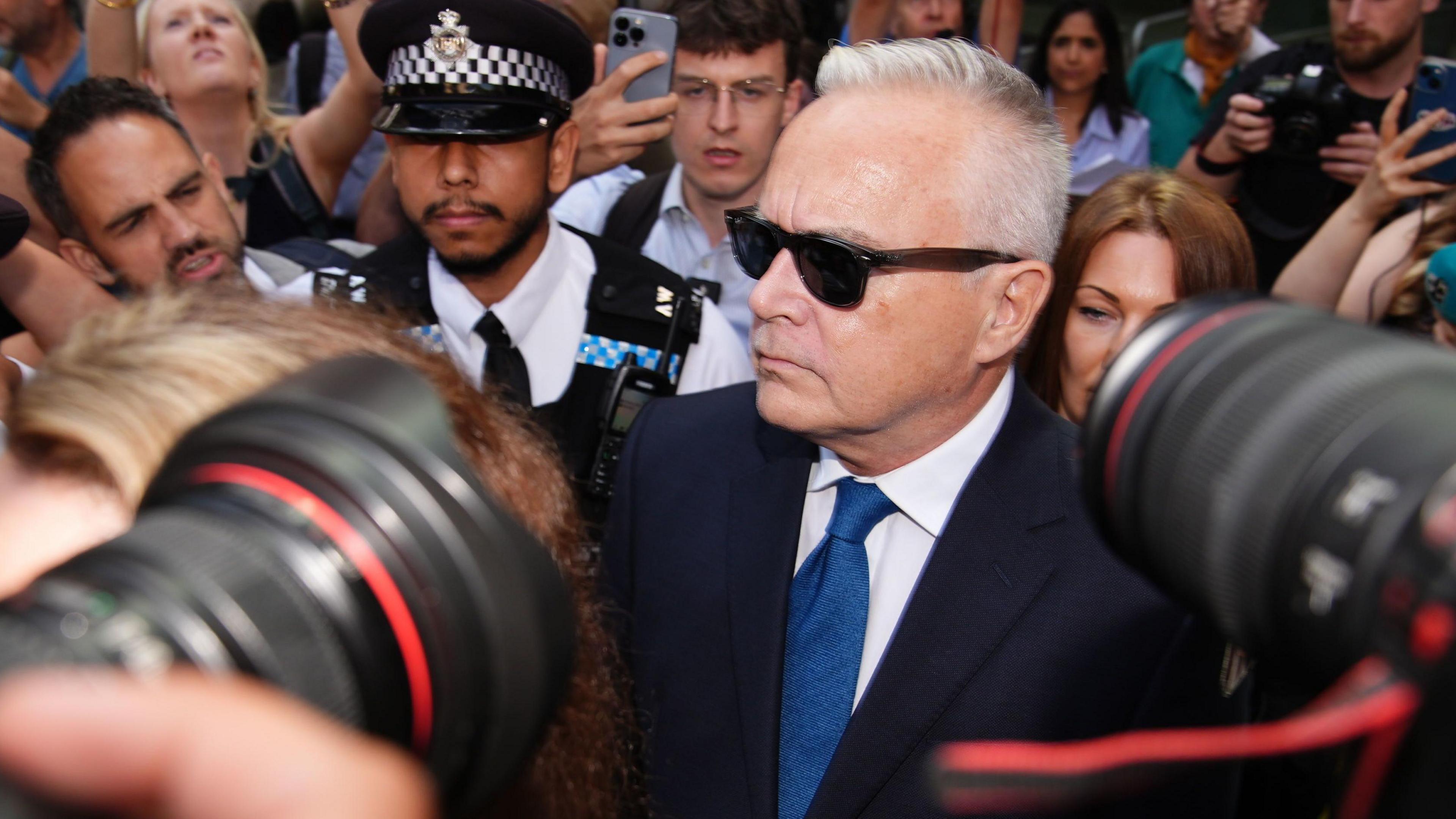 Huw Edwards arriving at court surrounded by police and photographers